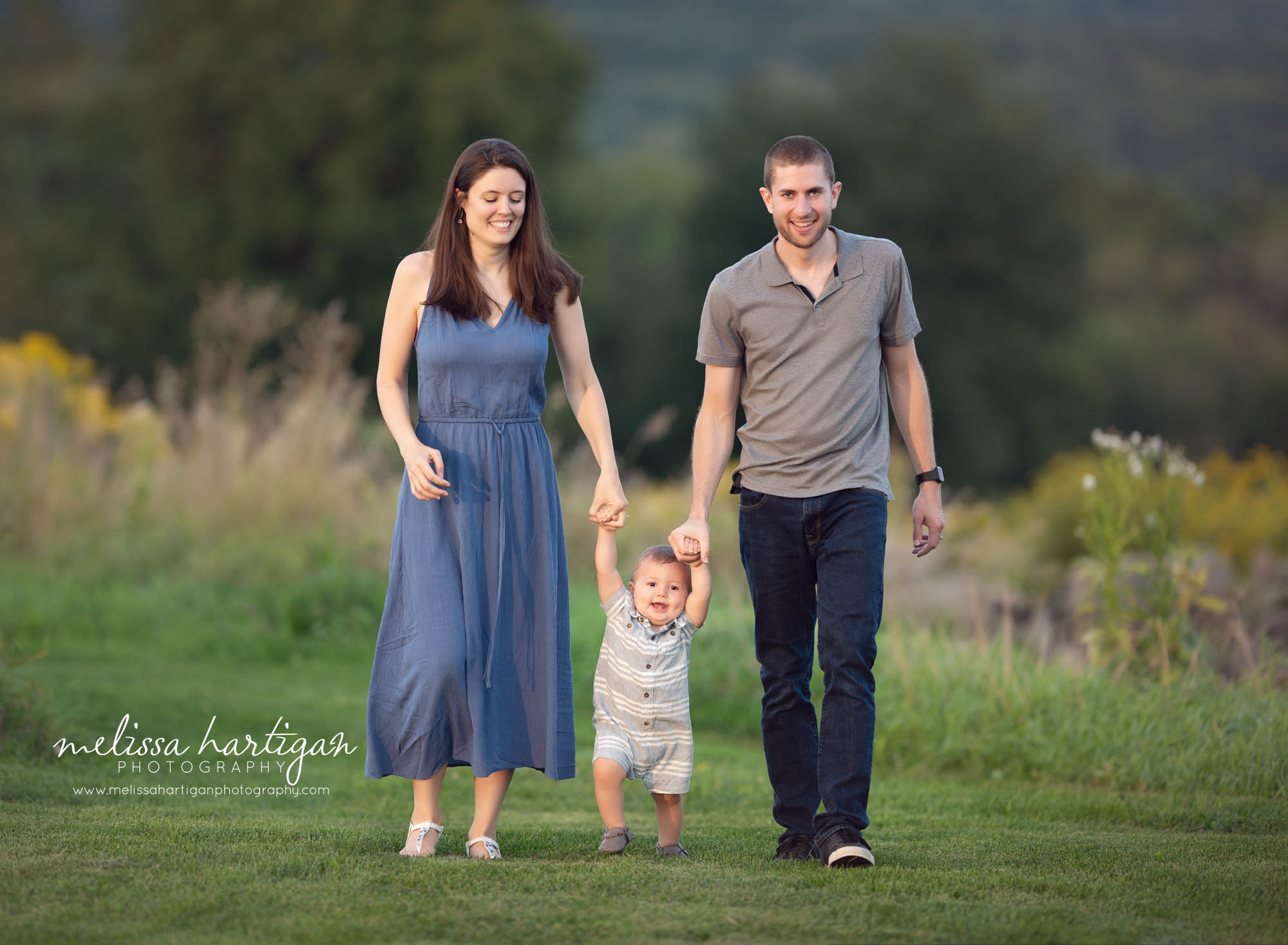 mom and dad holding toddler son's hands walking family photography
