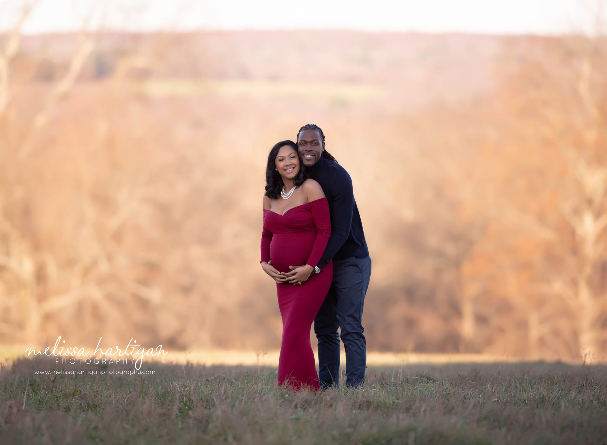expectant couple smiling looking at camera holding baby bump outside maternity photography CT