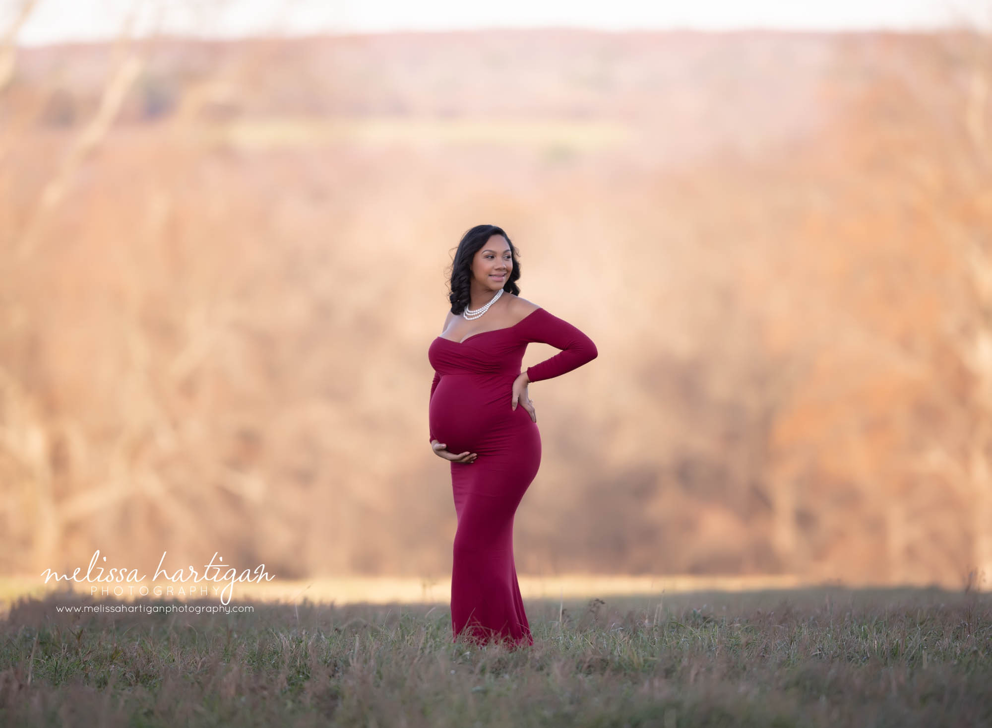 stunning pregnant mom holding baby bump looking to the side of her smiling outdoors maternity session CT maternity Photography New Britain