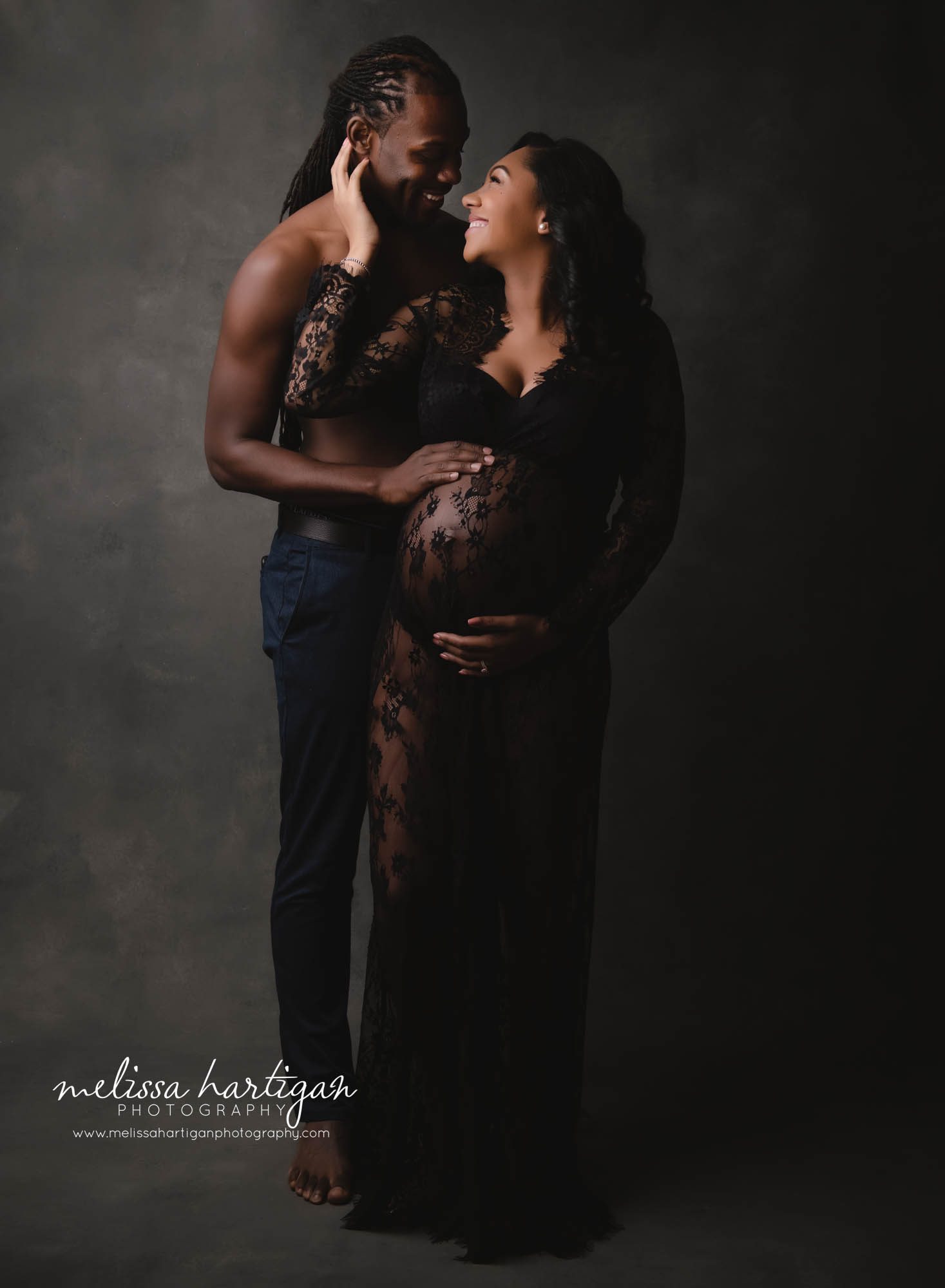 stunning pregnant mom and dad to be holding baby bump looking at each other studio maternity session CT maternity Photography