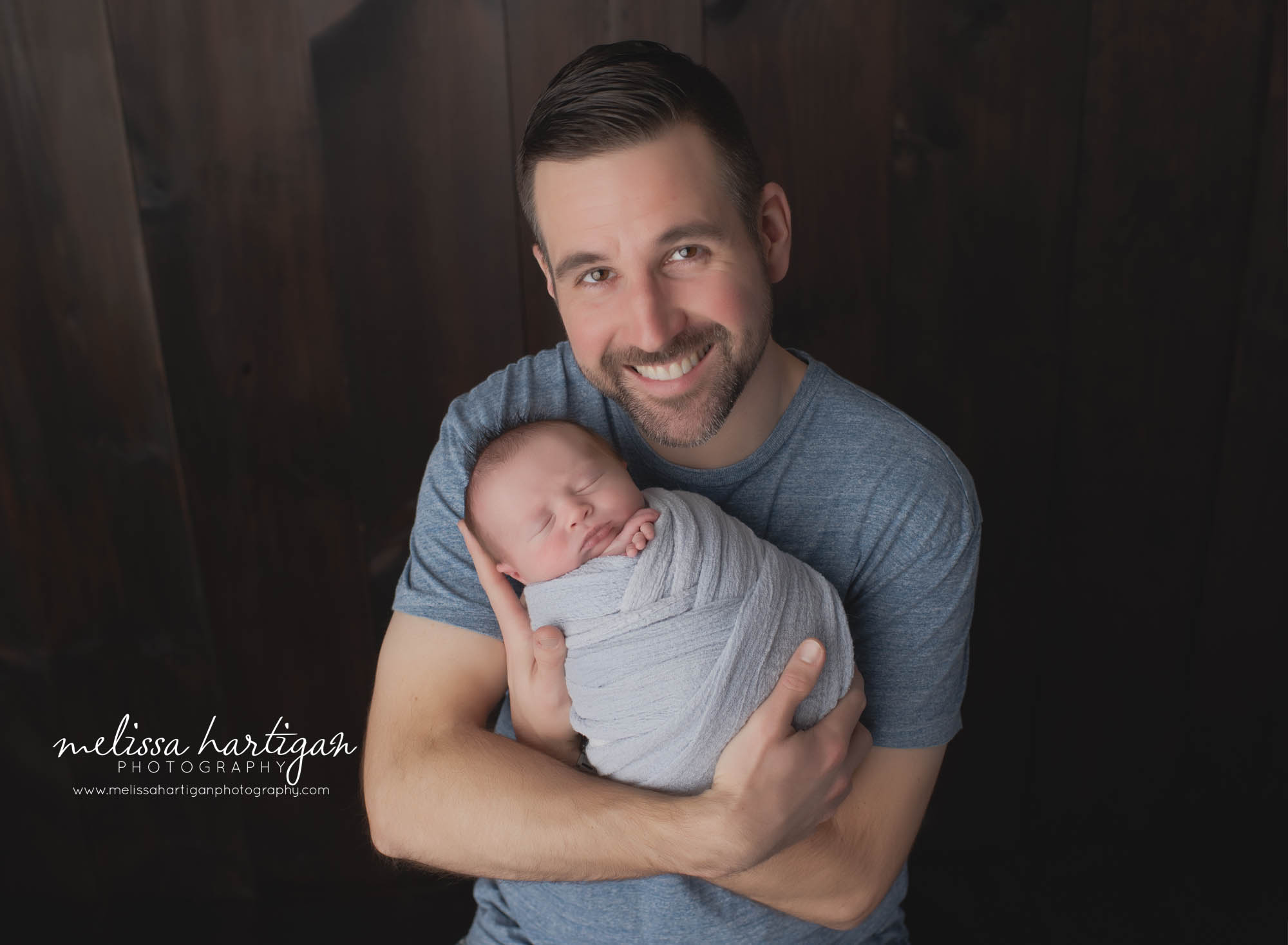 dad holding newborn baby boy wrapped in light blue wrap newborn family photography session CT photographer