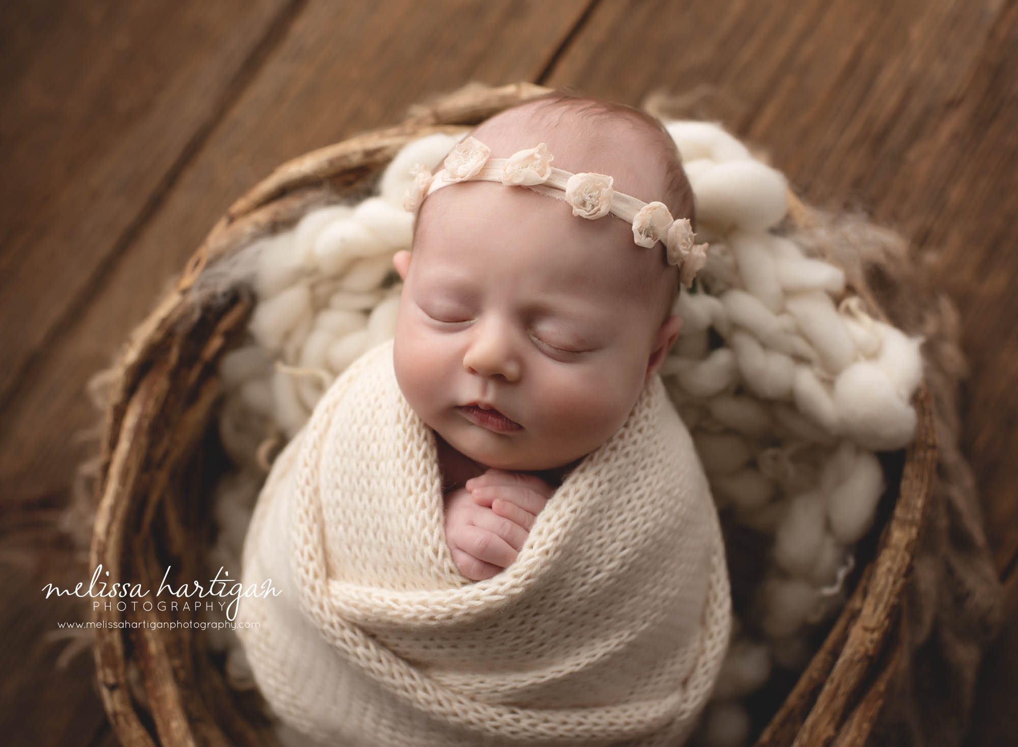 baby girl wrapped in knitted cream wrap with floral cream colored headband Ct newborn photographer