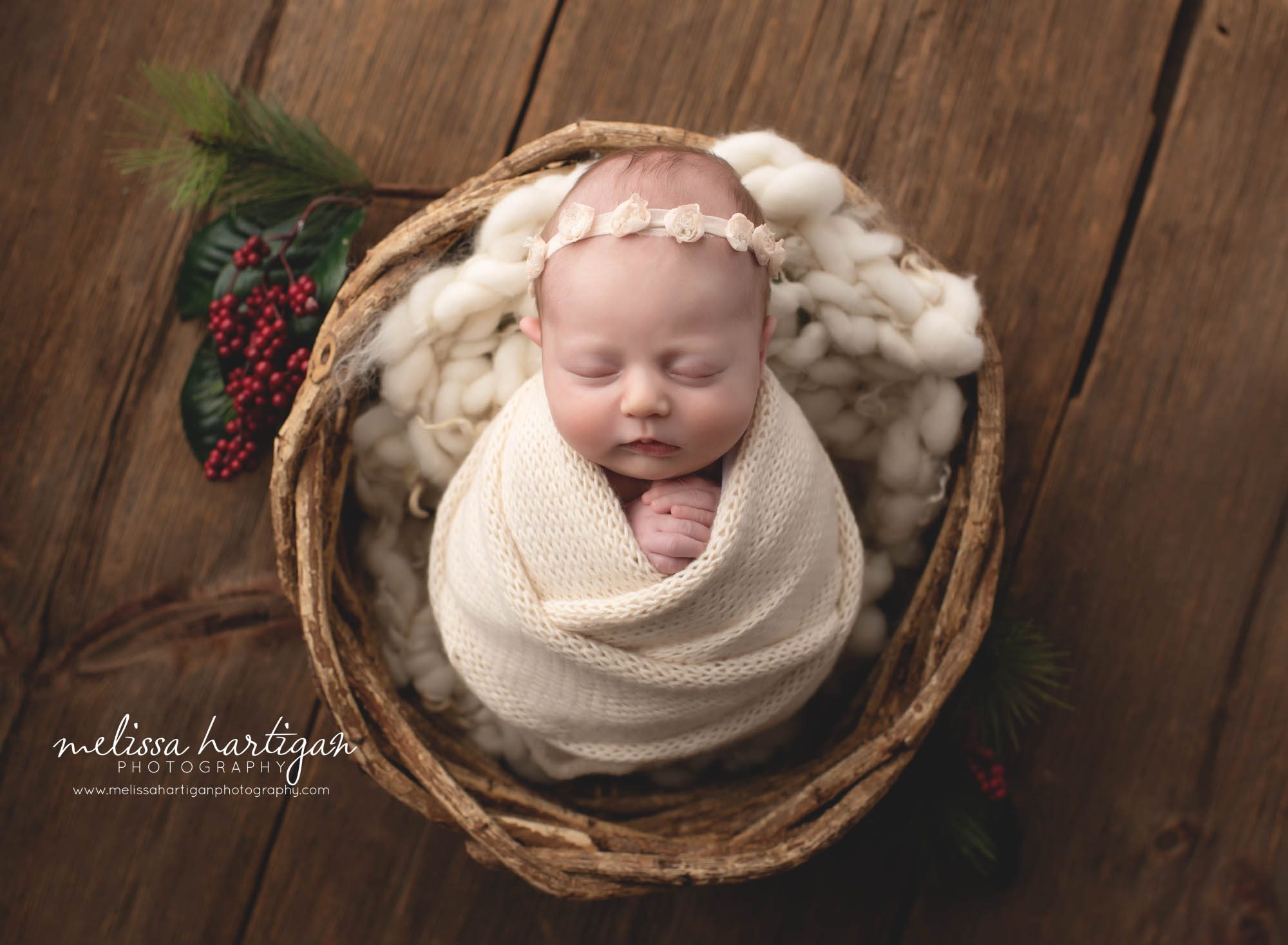 newborn baby girl wrapped in cream wrap knitted cream chunky knitted layer posed in wicker basket with holiday berry element ct newborn photography