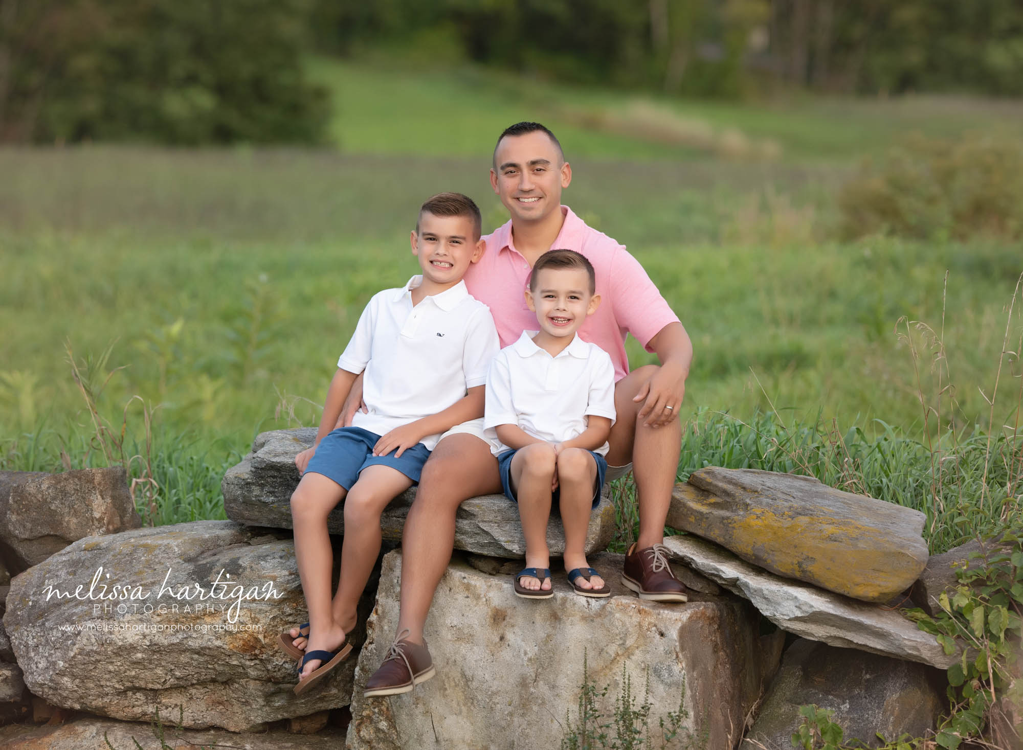 Dad and two young sons sitting on rocks family photography session connecticut park