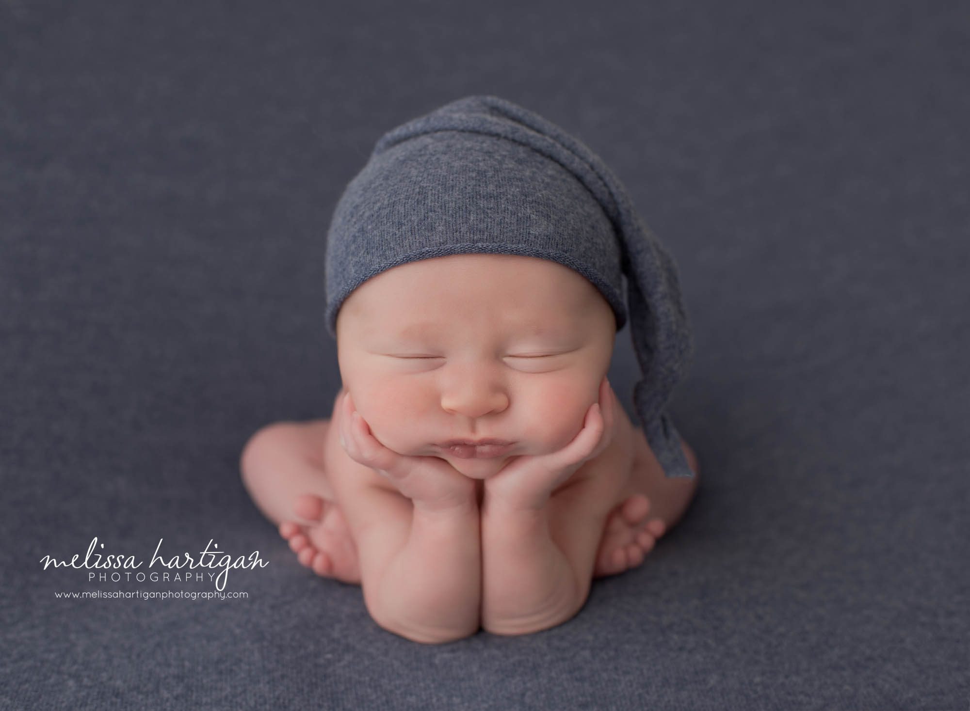 newborn baby bpy posed froggy pose with blue sleepy cap on