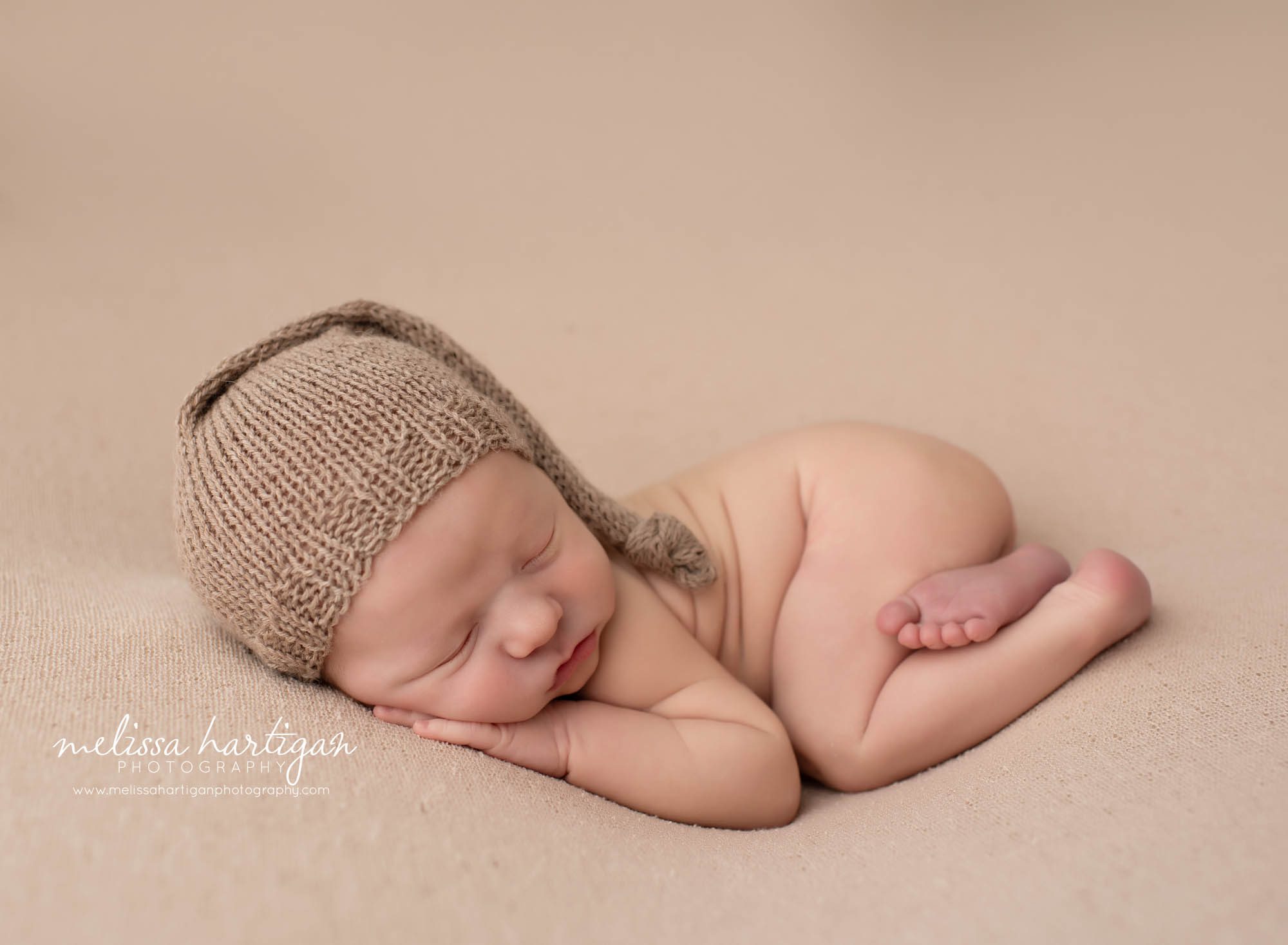 Newborn baby boy posed on tummy tan colored knitted sleepy cap CT newborn Photographer