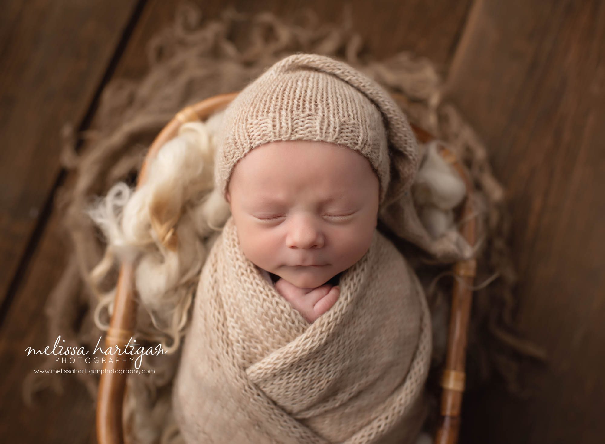 Baby boy wrapped in basket with cream layer and knitted sleepy cap