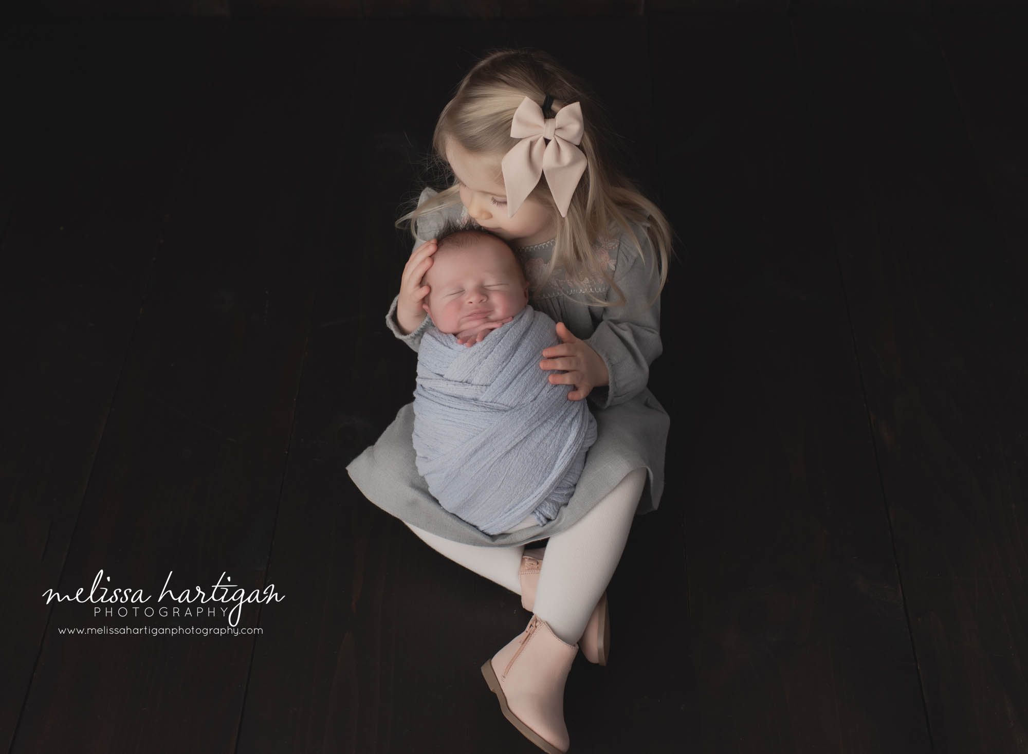 older sister holding wrapped newborn baby boy sibling pose newborn family photography Tolland