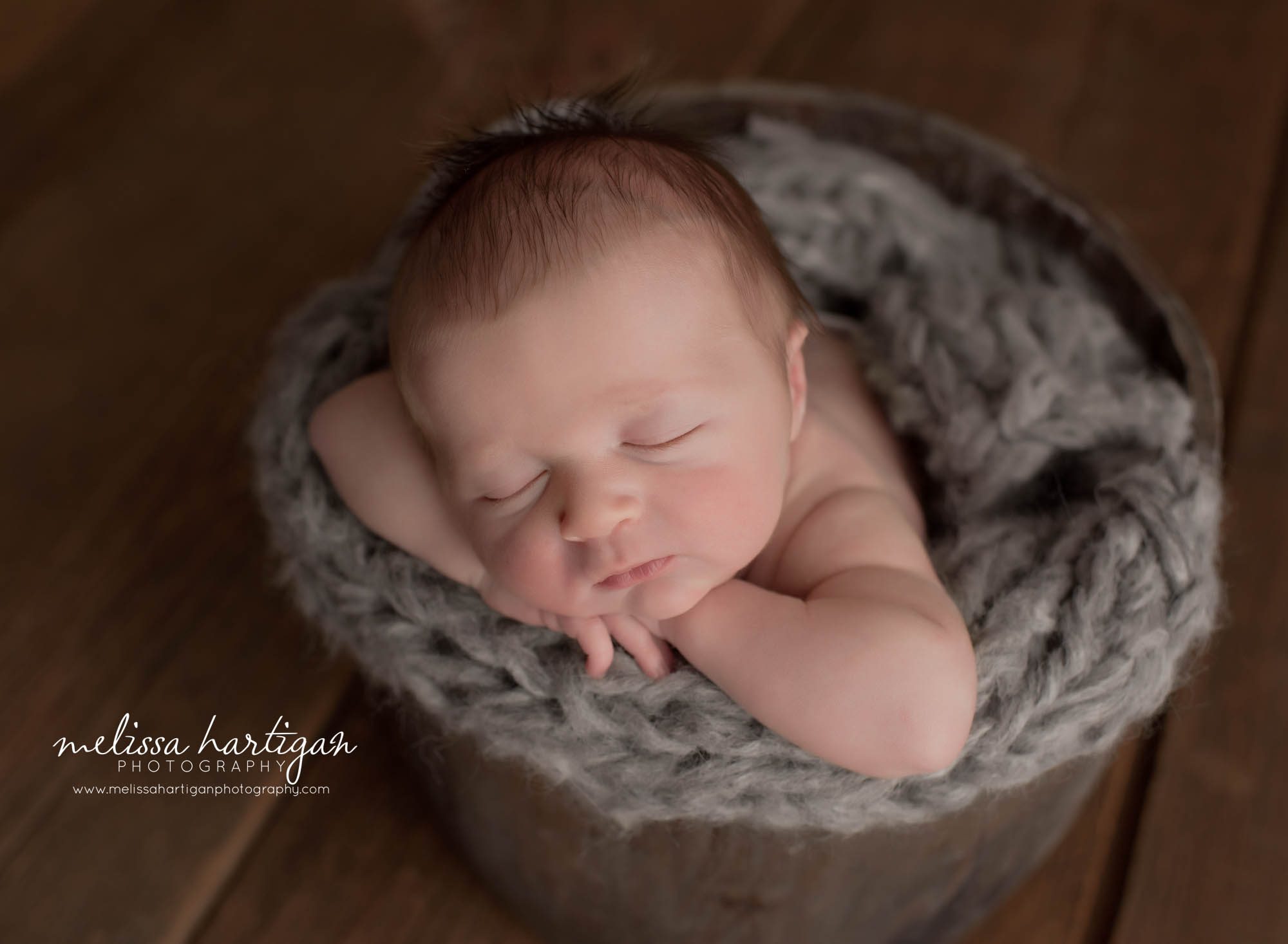 baby boy posed in wooden bucket with chin on hands newborn photographer tolland