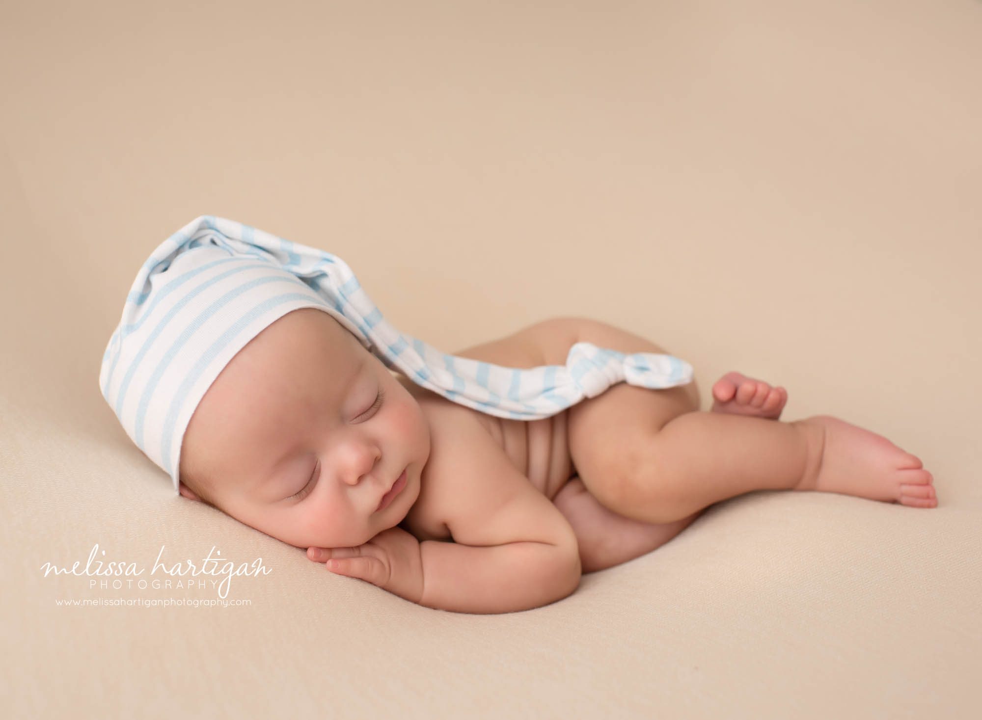 newborn baby boy pose don side with sleepy cap on