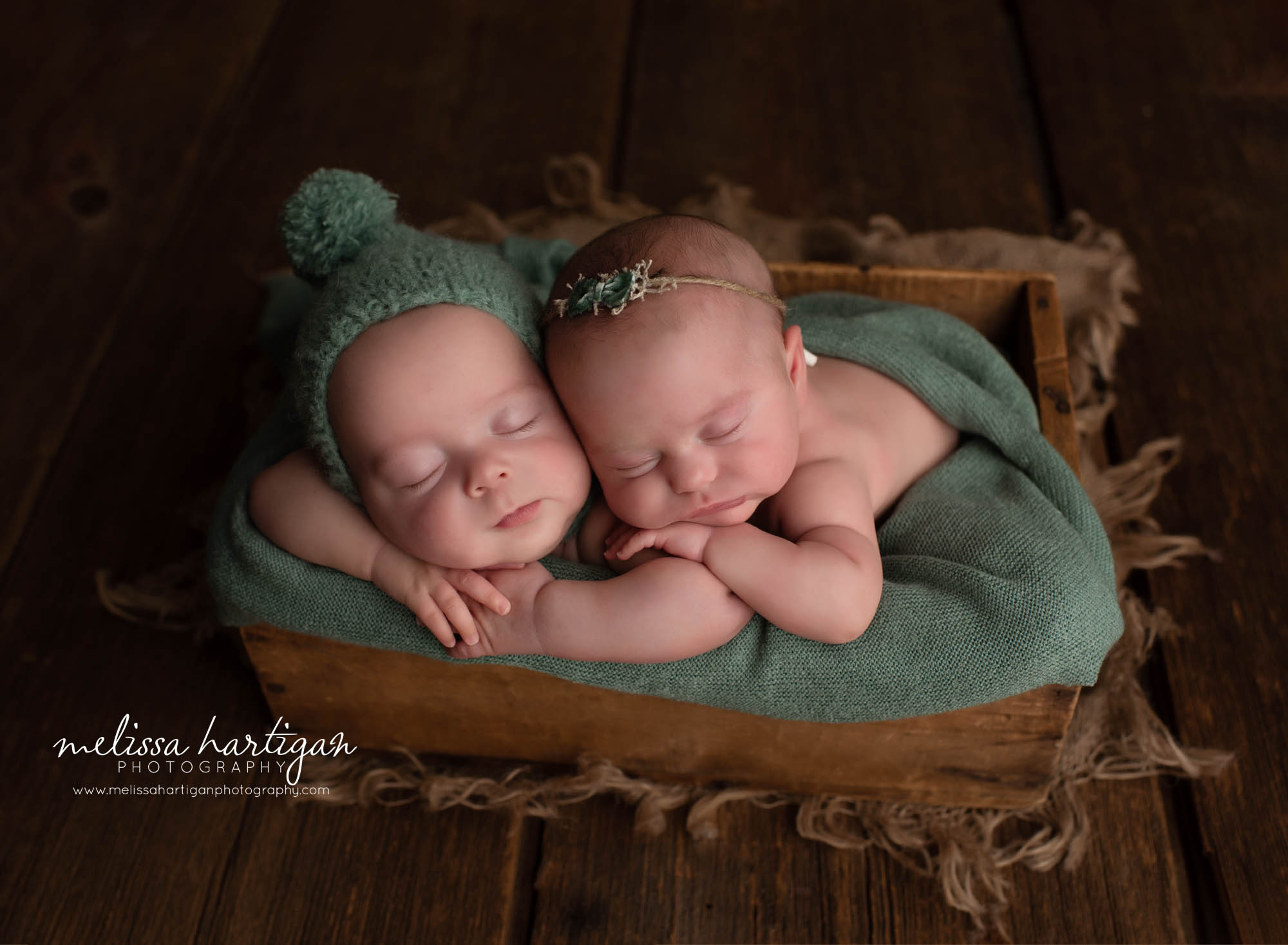 boy girl twin babies posed together in wooden crate with green layer wrap pom sleepy cap and floral tie back newborn photography connecticut