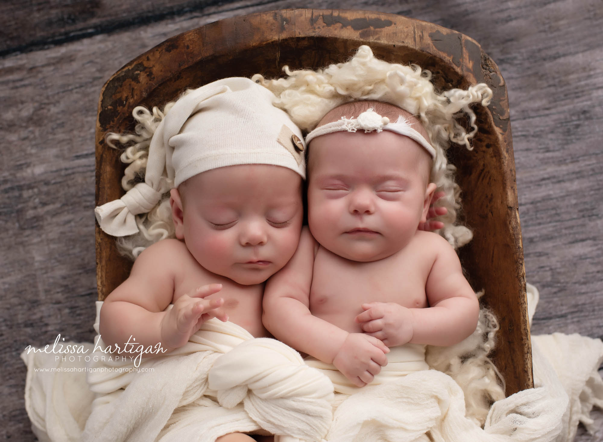 twin newborn babies posed together in wooden prop with cream layers and colors