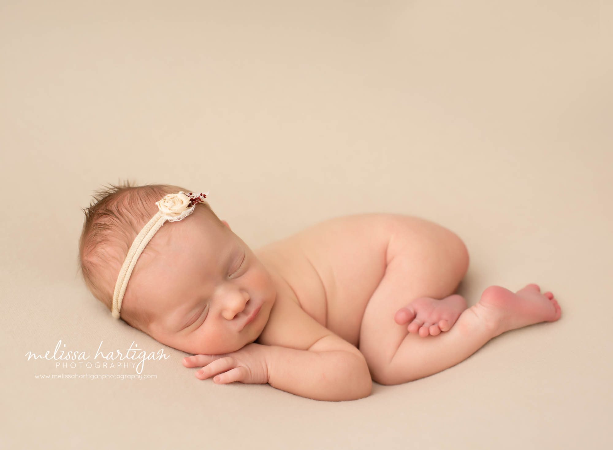 Newbonr baby girl posed on side with bum up wearing cream headband with flower Connecticut newborn photographer