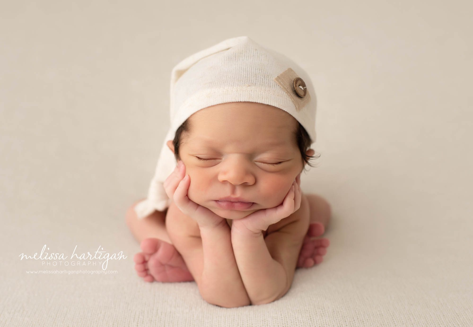 newborn baby boy wearing cream colored sleepy cap posed froggy pose newborn photography CT