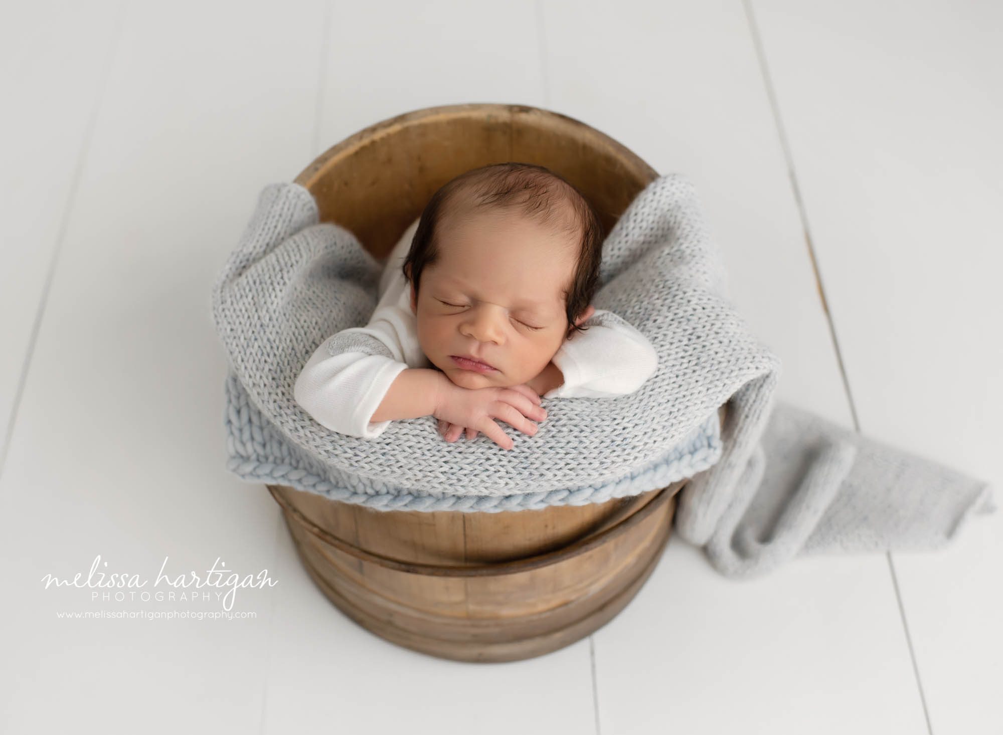newborn baby boy posed in wooden bucket with light blue knitted wrap CT newborn photography
