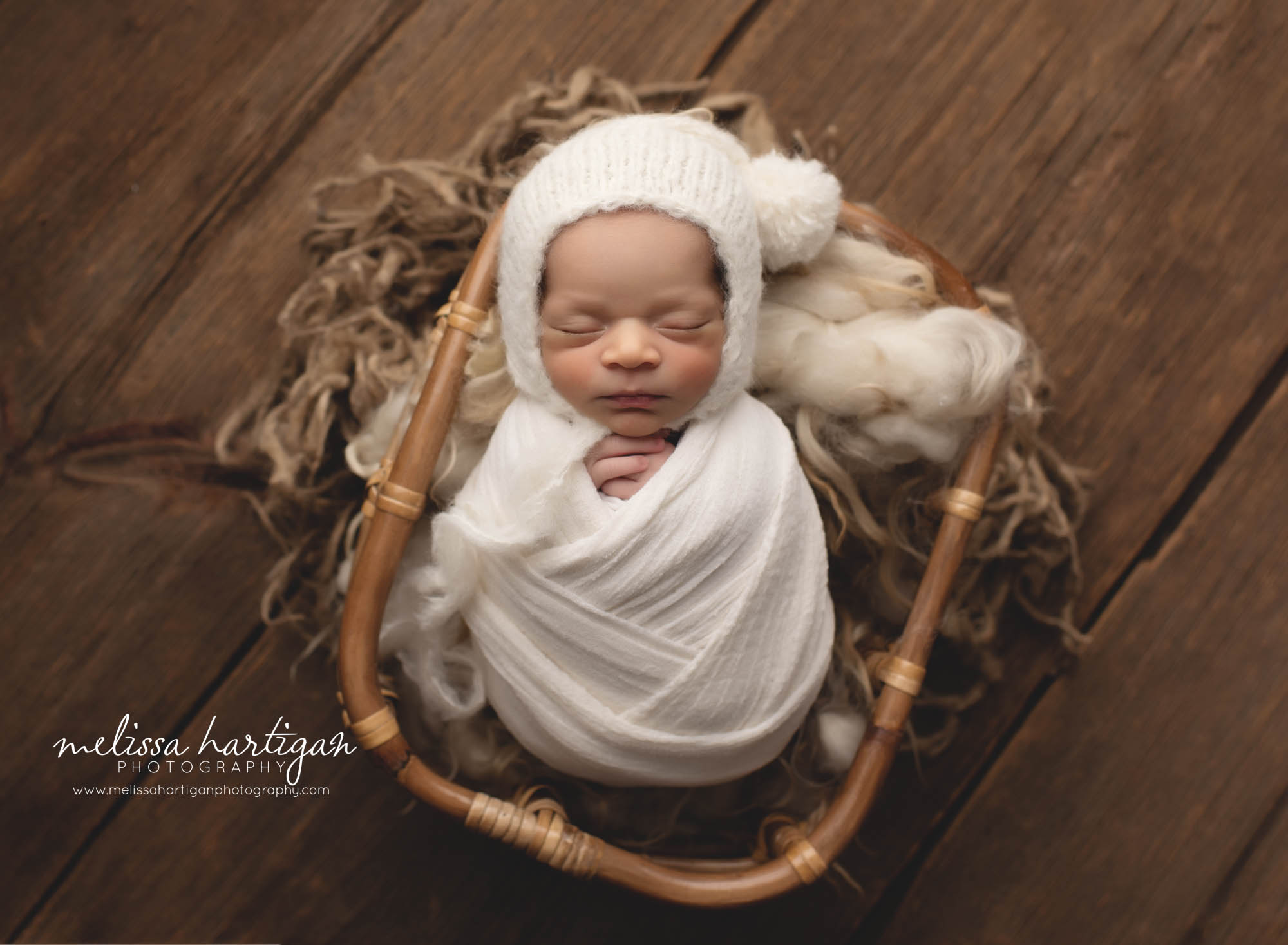 newborn baby boy wrapped in white wrap knitted pom sleepy cap