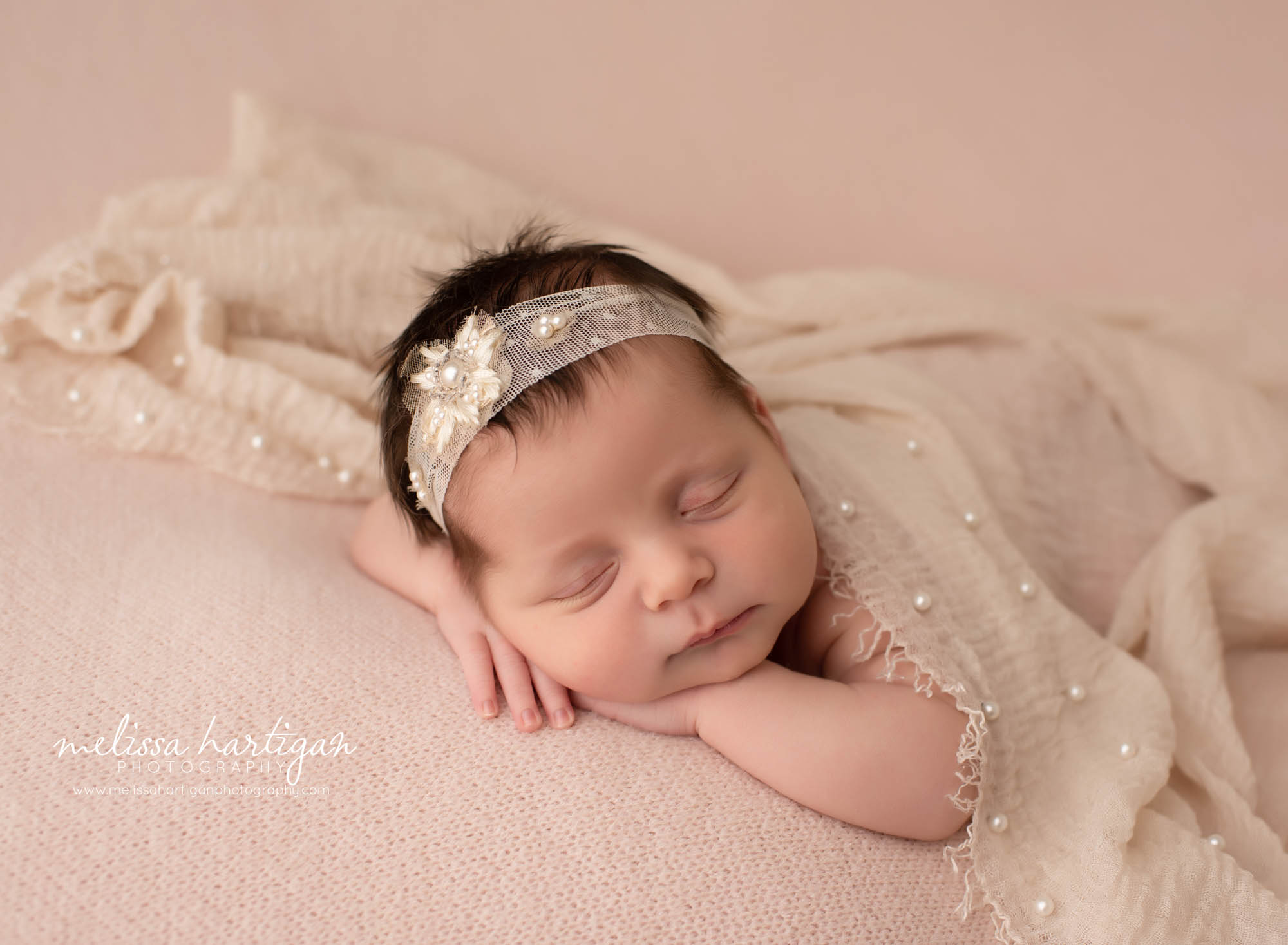 newborn baby girl posed on pink blanket with beige wrap layer and lace headband newborn photographer CT