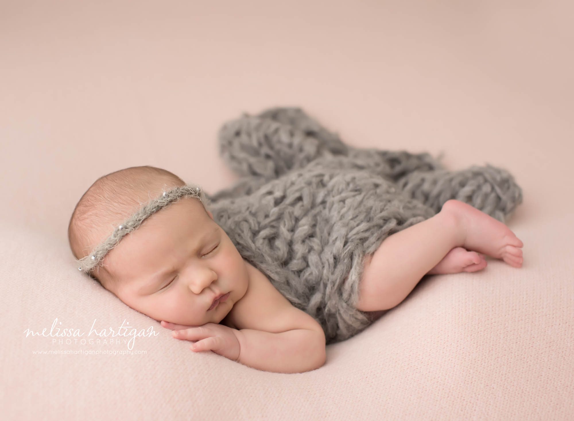 Newborn baby girl posed on side with light gray headband and knitted layer connecticut newborn photography