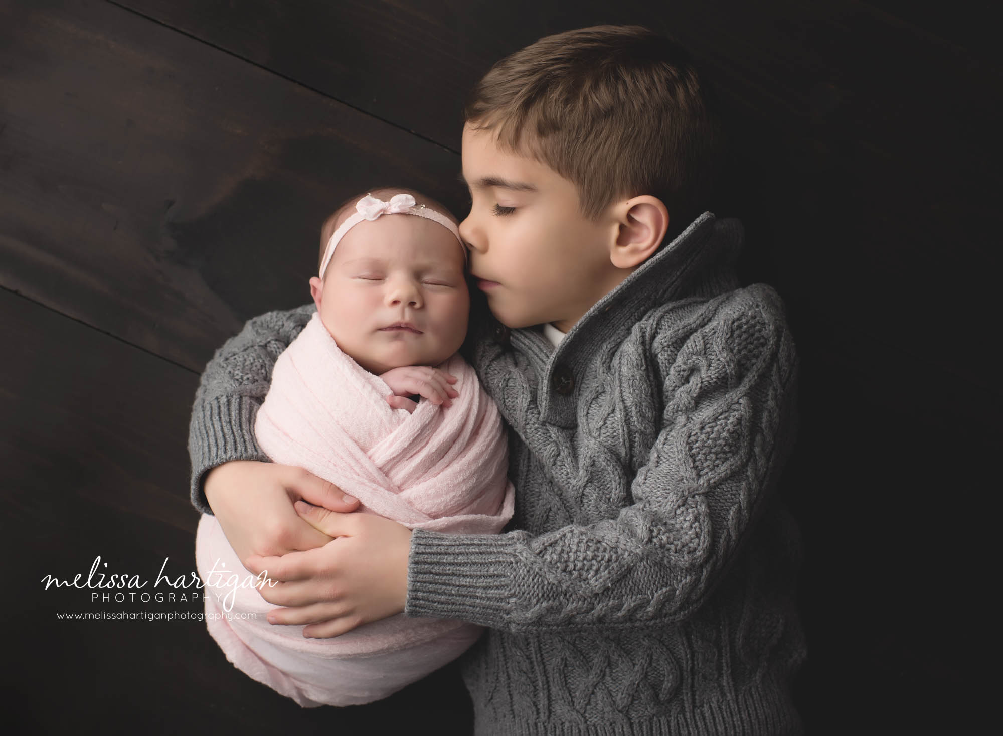 big brother laying down hugging newborn baby sister studio photography session Coventry Newborn photographer