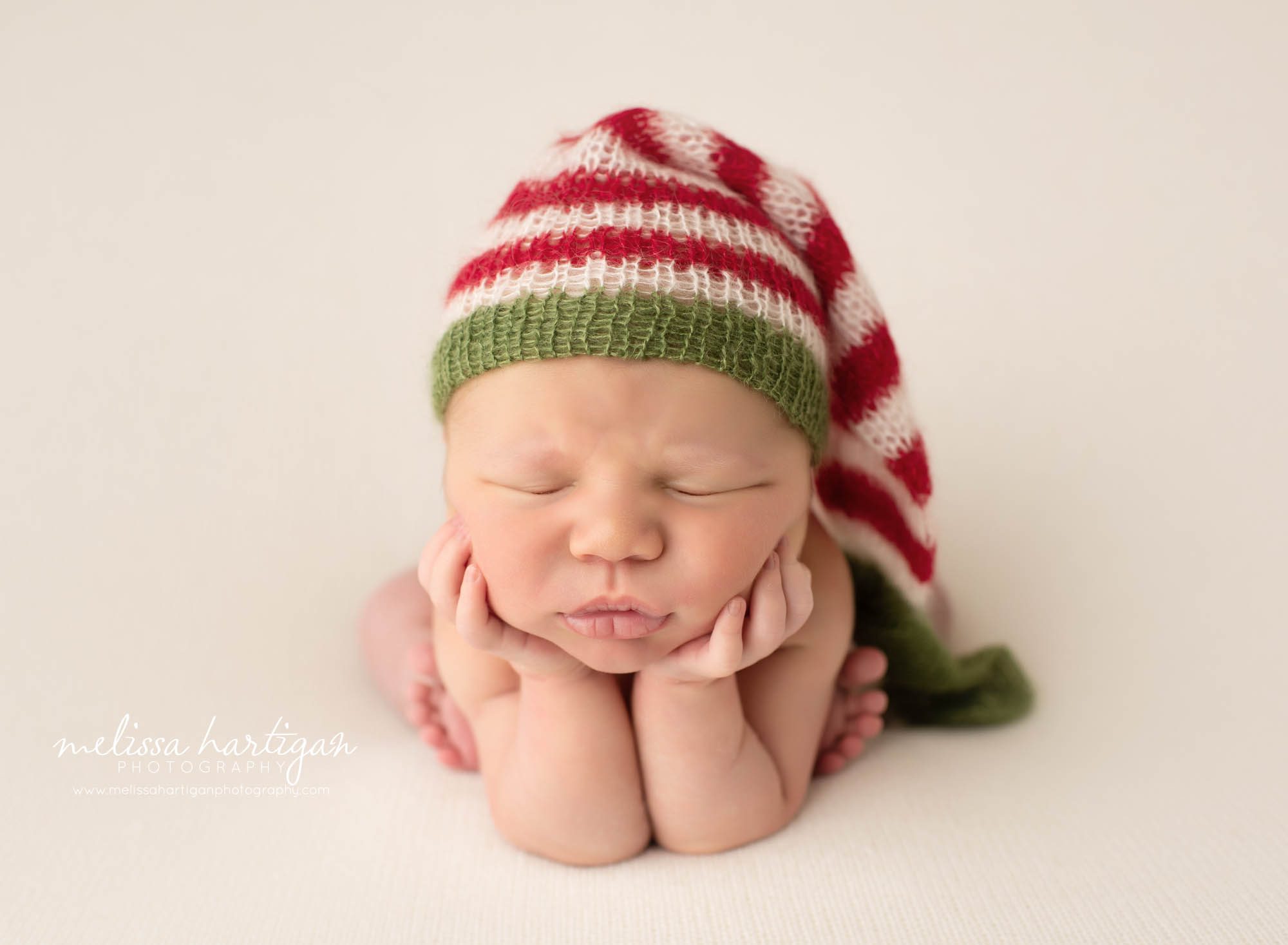 newborn baby boy posed froggy pose christmas color knitted sleepy cap