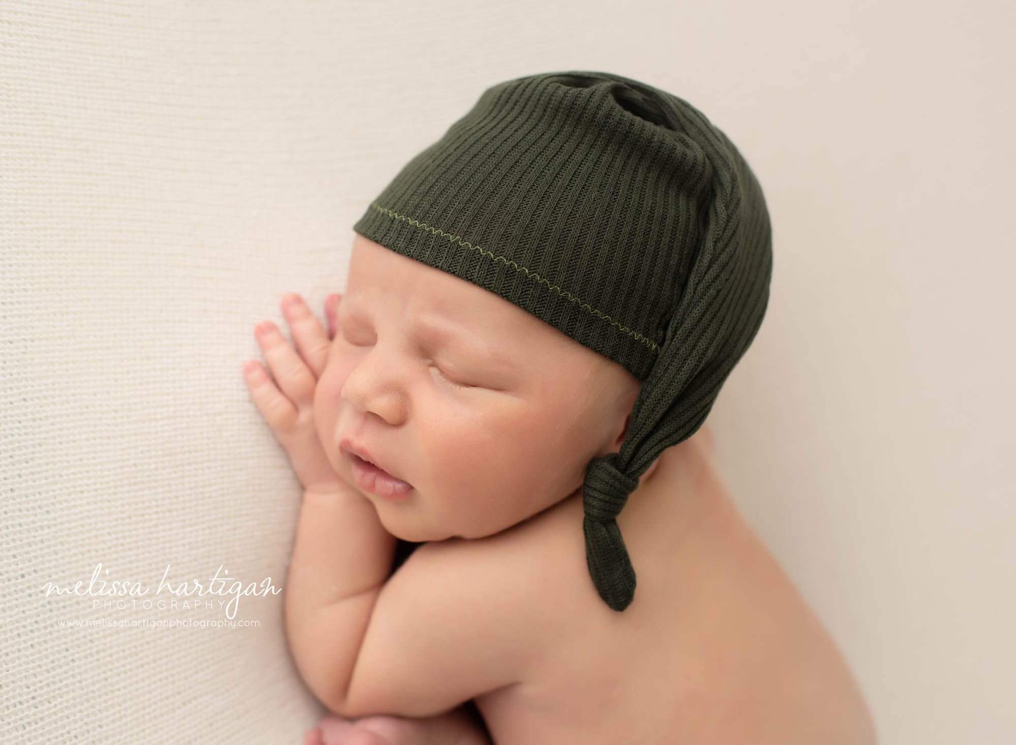 newborn baby boy posed on side with green sleepy cap Newborn Photographer Woodbridge CT