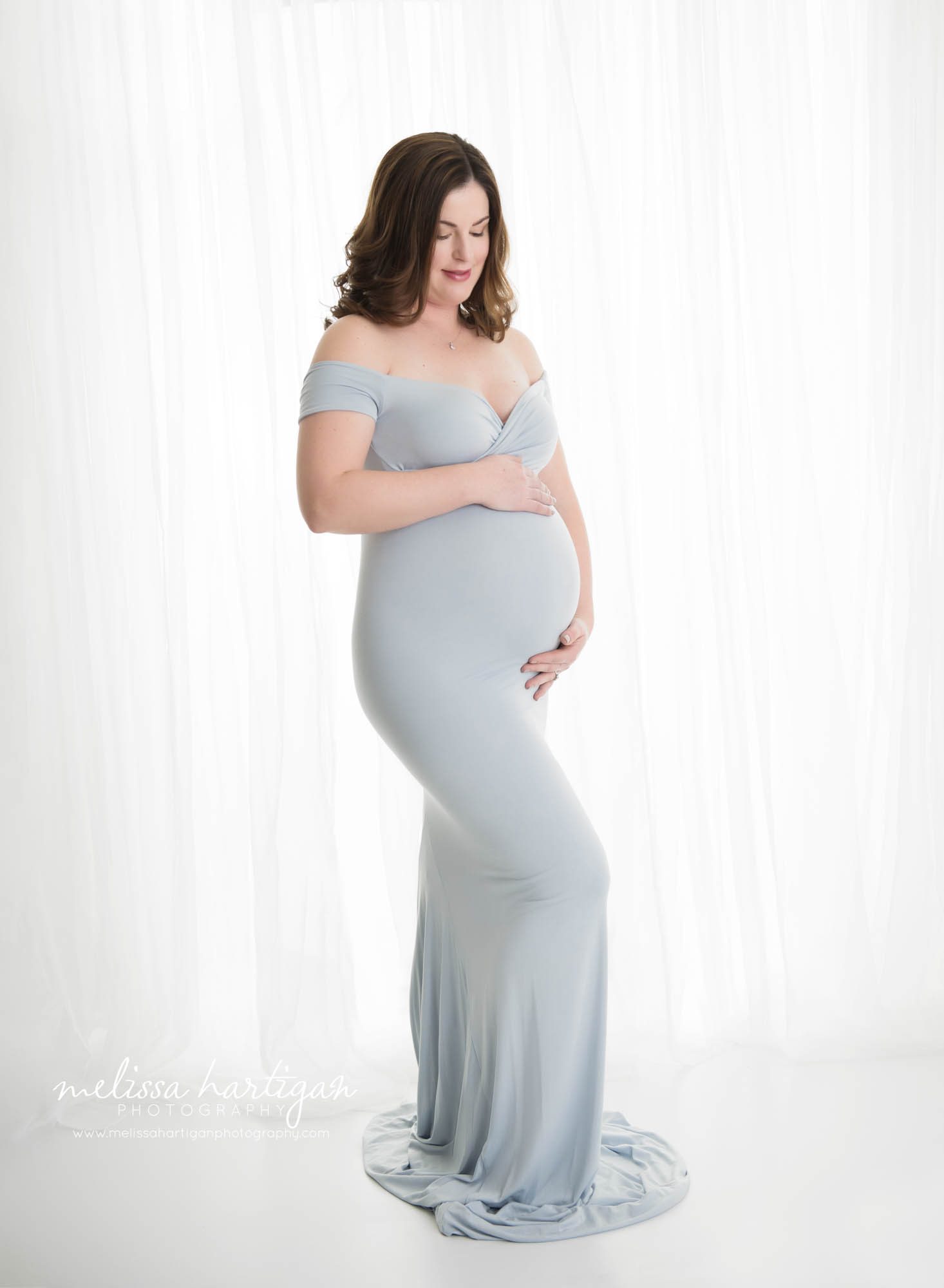 studio maternity session with pregnant mom holding baby bump ooking down at baby bump
