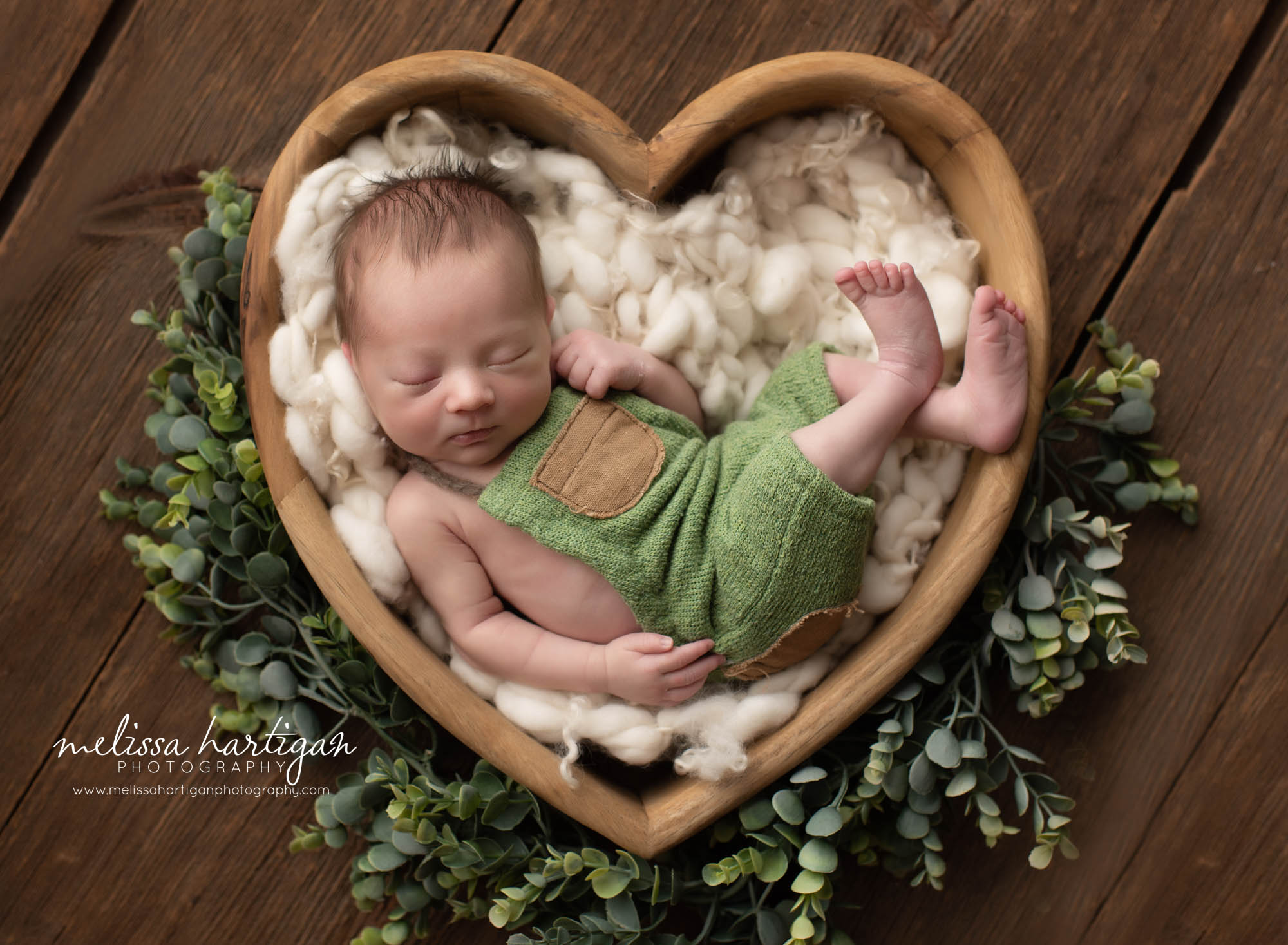 newborn baby boy posed in wooden heart prop wearing green newborn baby boy outfit Newborn Photographer CT
