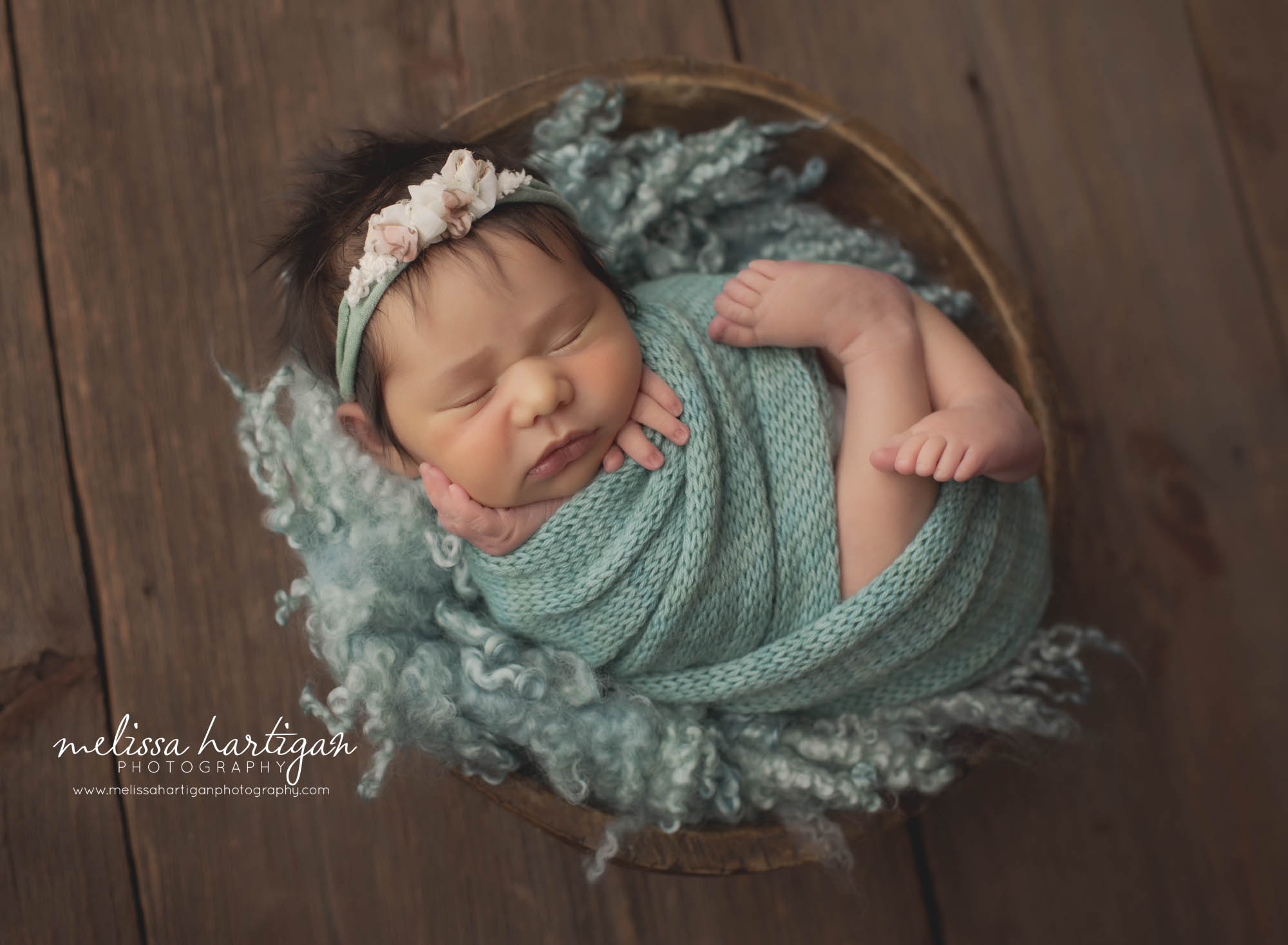 newborn baby girl wrapped in sea green knitted wrap with headband and curly layer
