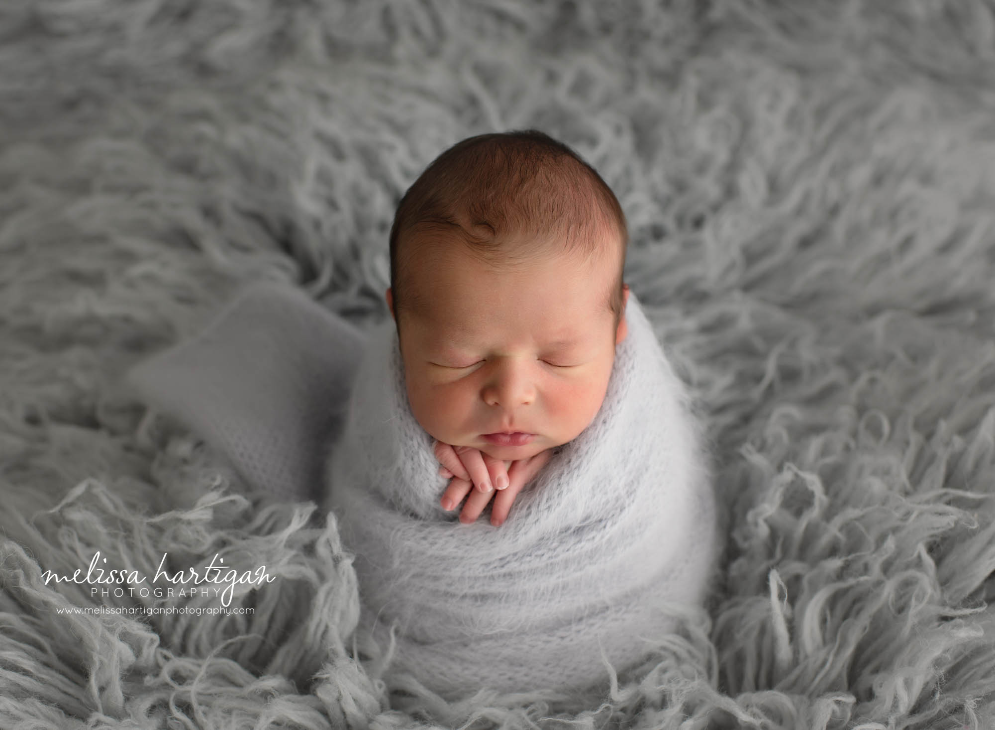 newborn baby boy wrapped in gray knitted wrap posed on gray flokati CT newborn photography
