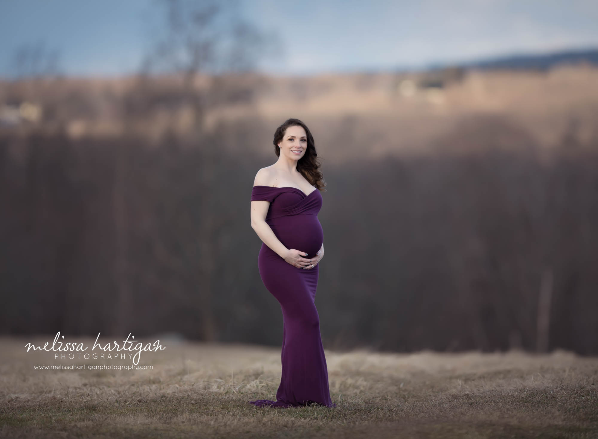 pregnant mom standing maternity pose outside wearing long purple form fitting maternity gown maternity photography CT