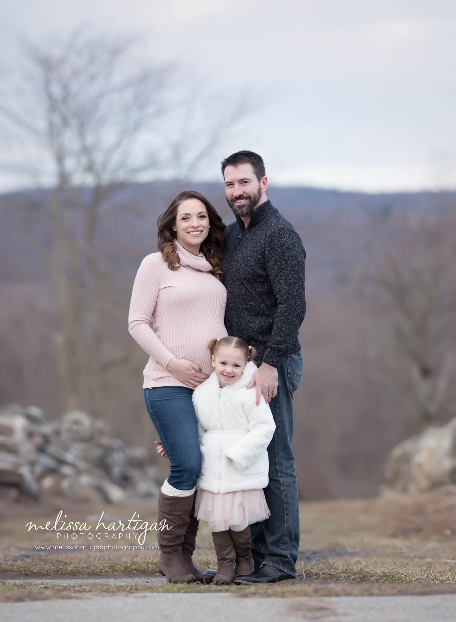 Mom dad and big sister to be standing family maternity pose outside maternity photography CT