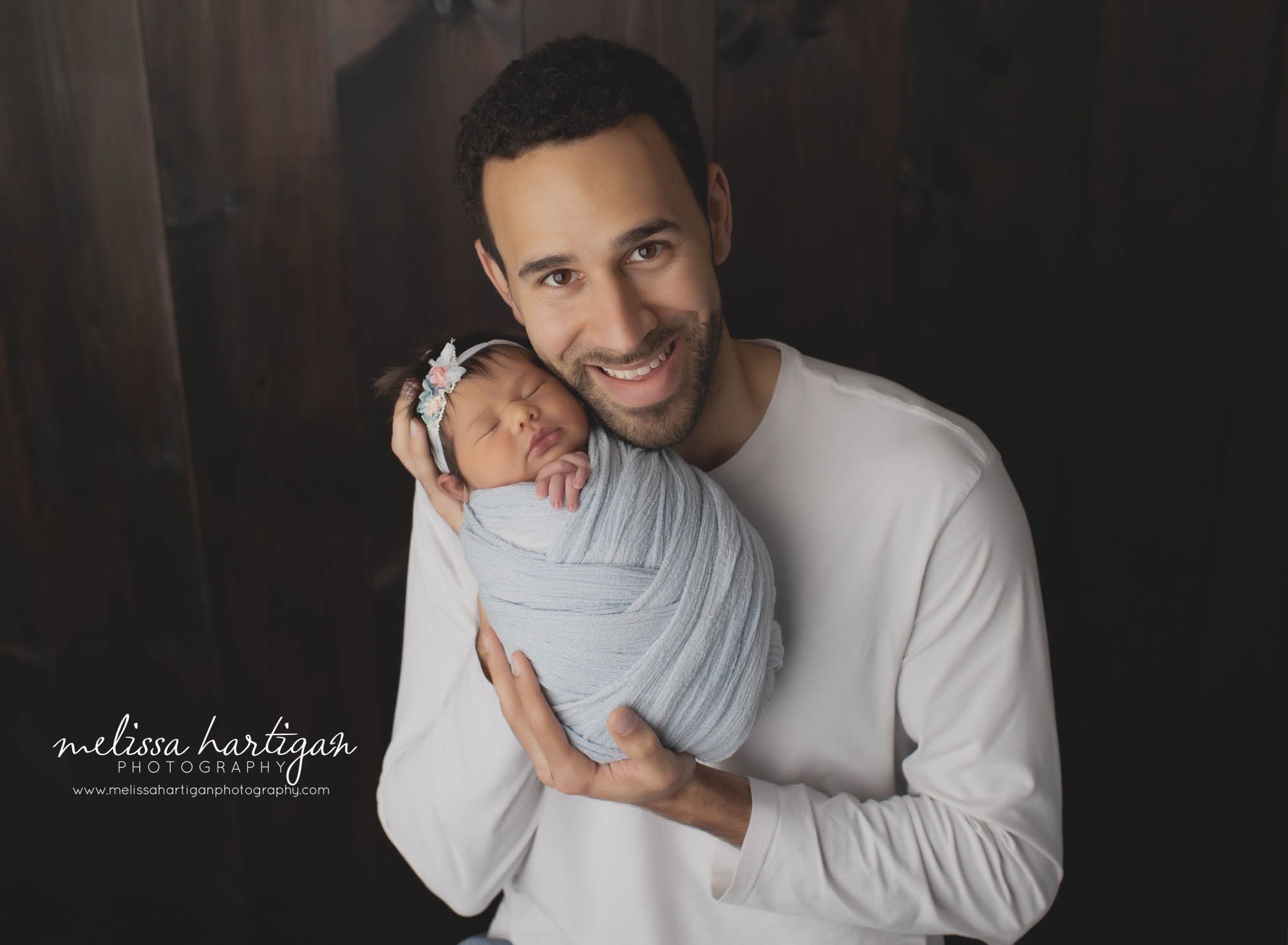 dad holding newborn baby girl in newborn studio photography session