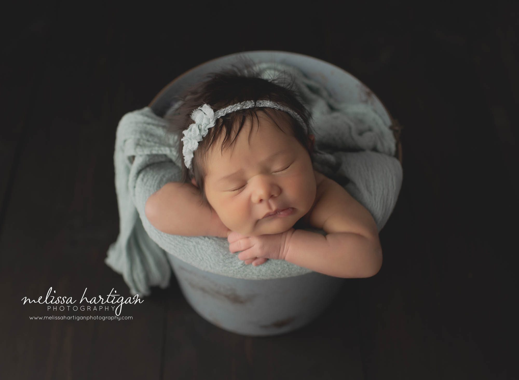 newborn baby girl posed in metal bucket with sea green wrap and bow headband tiebacknewborn Photography