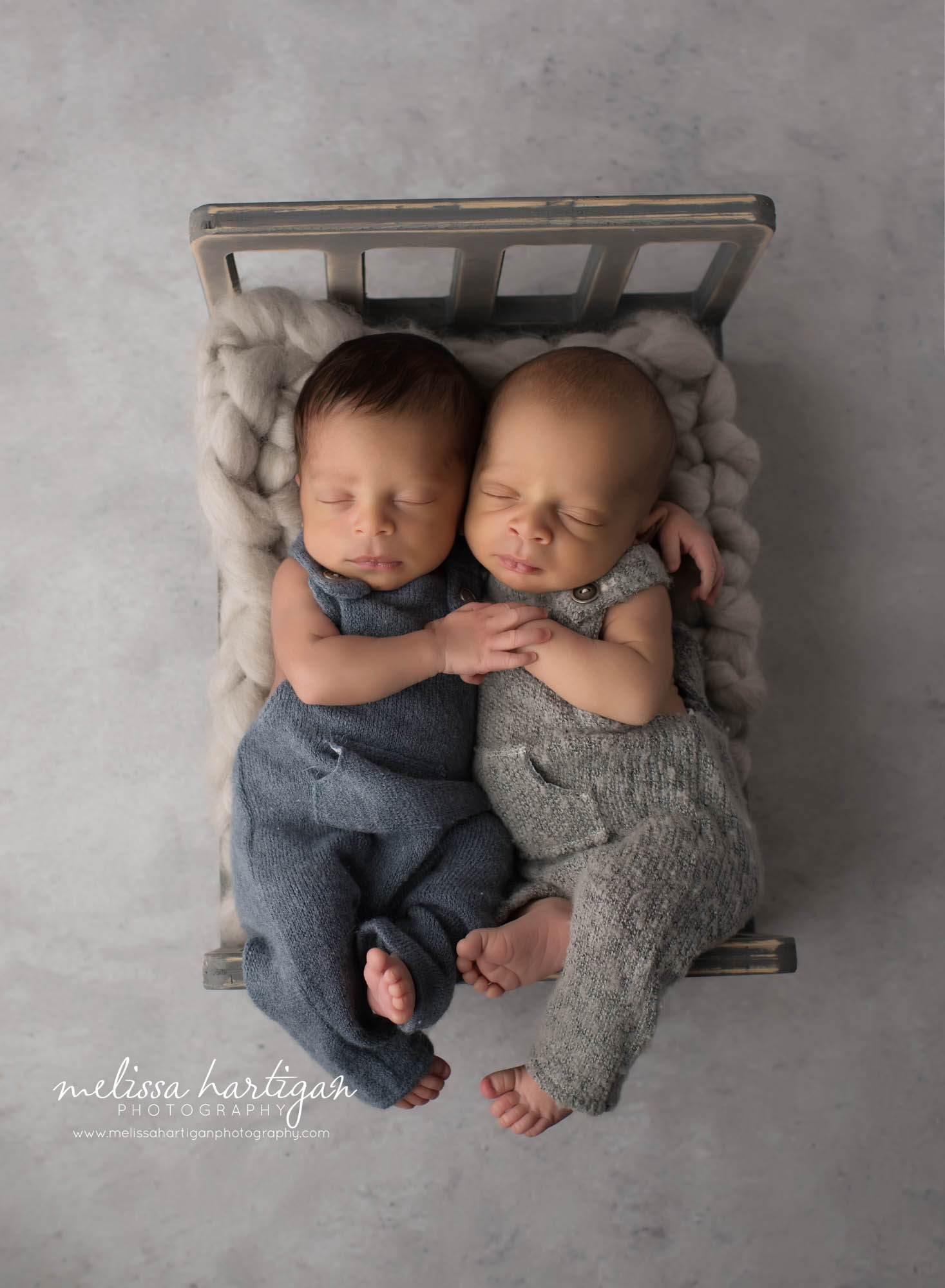 newborn twin boys posed on wooden bed prop wearing blue and gray newborn outfits CT newborn Photography