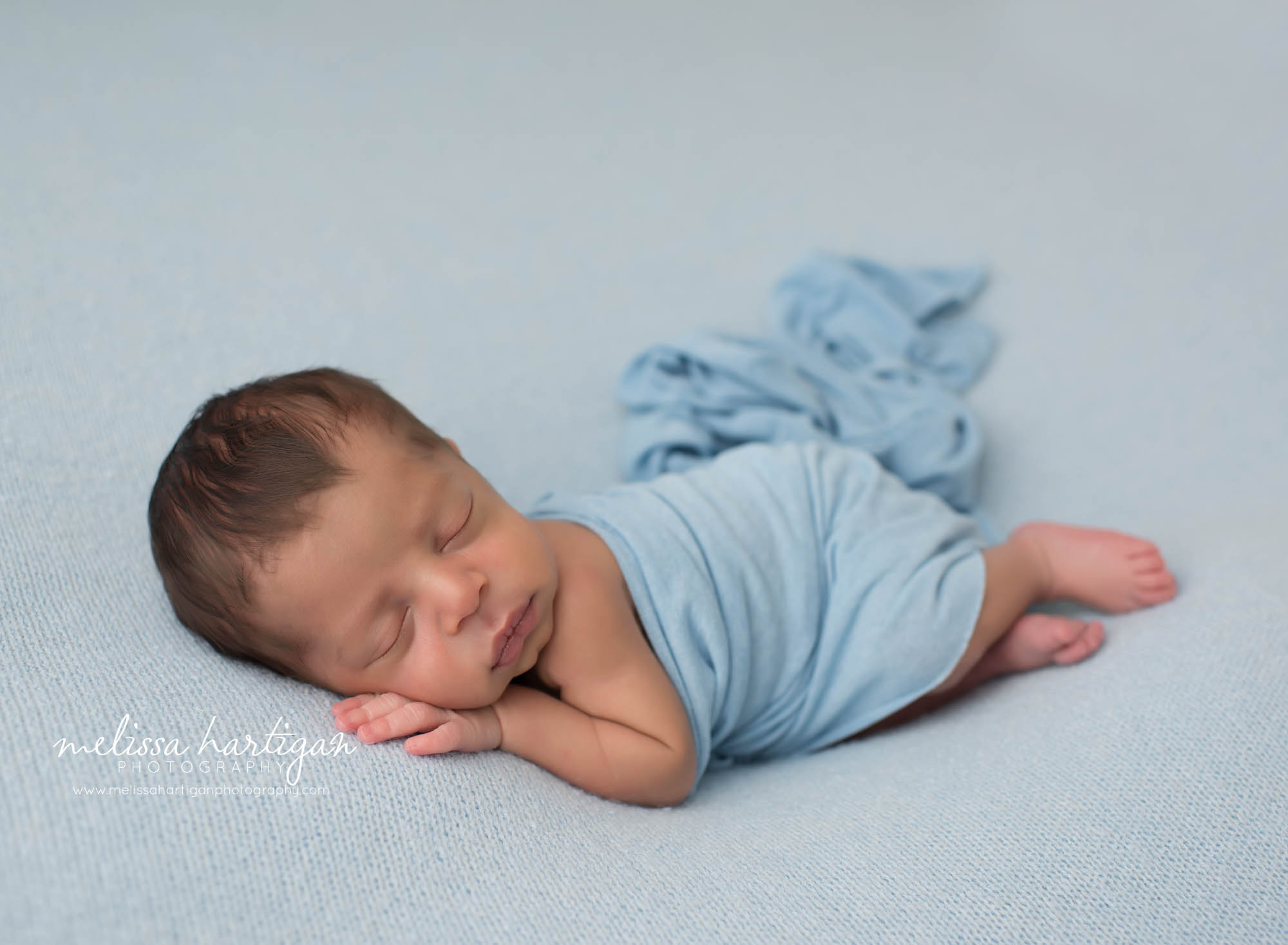 Baby boy posed on blue backdrop with blue lay wrap draped over him Newborn Photographer CT