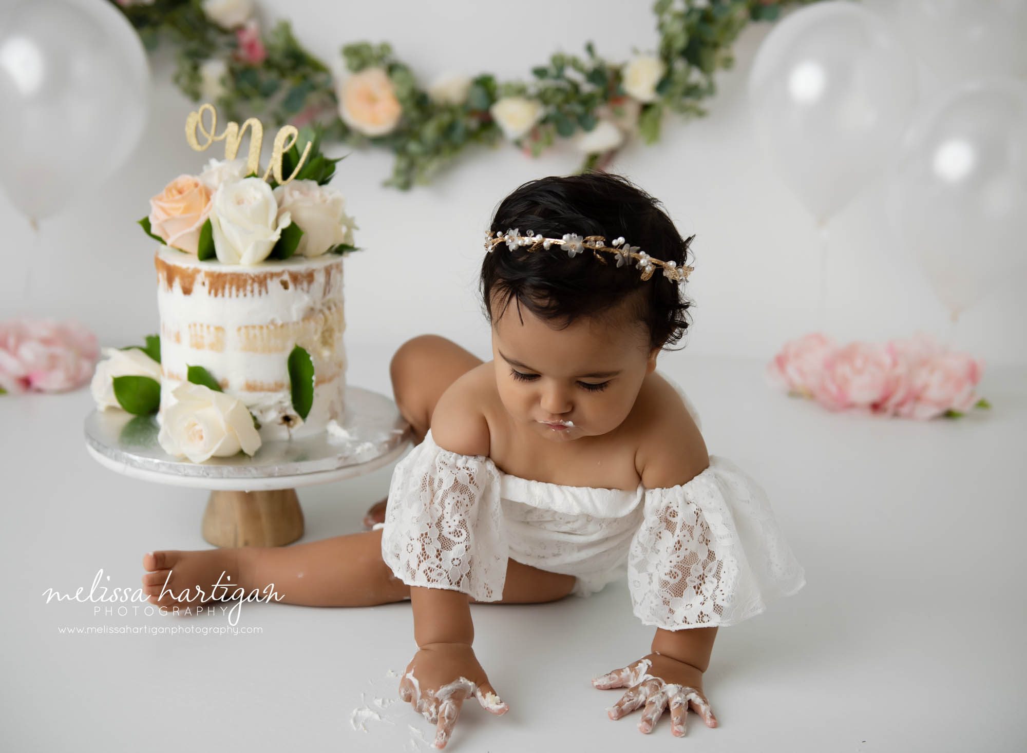 Baby girl laying in icing from cake smash cake studio milestone photographer