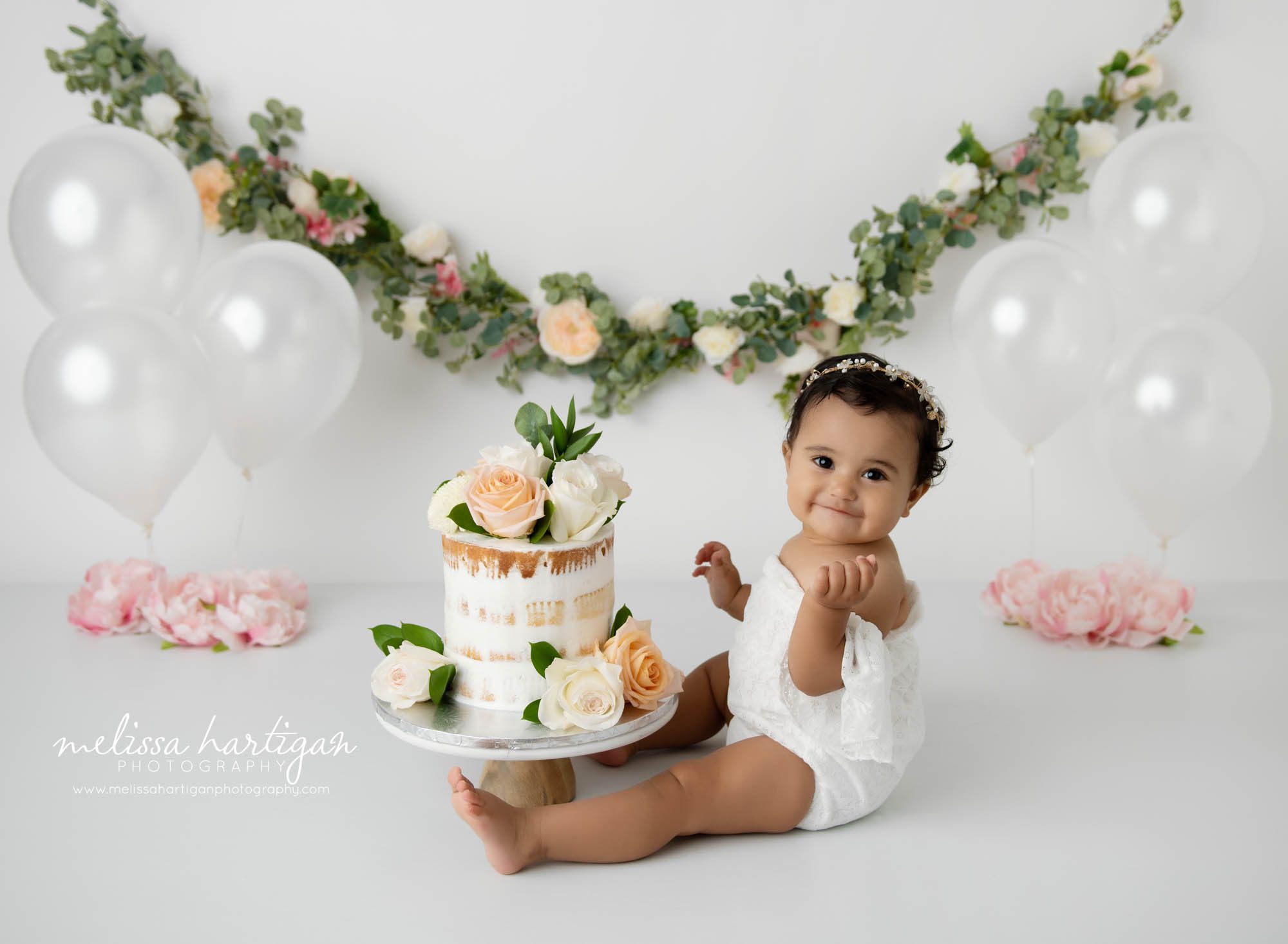 baby girl smiling at camera sitting in front of cake smash cake Middletown CT Baby Photography