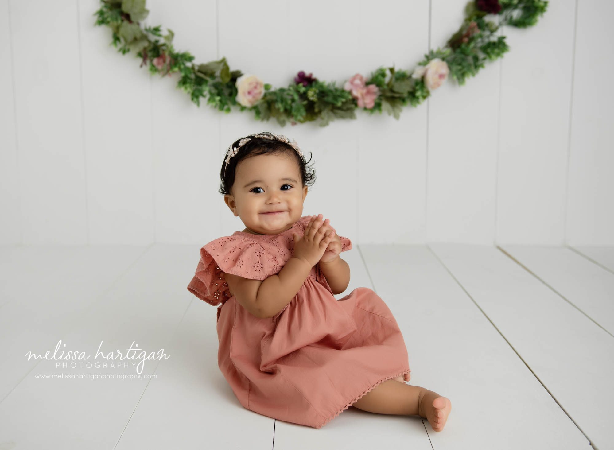 baby girl sitting on wood boards wearing pink dress studio milestone photographer