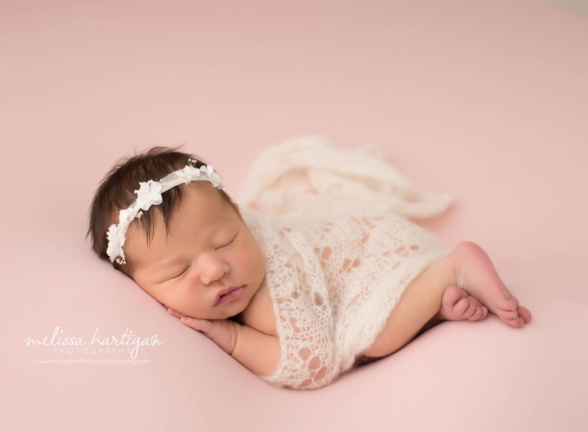 newborn baby girl posed on side with hand under chin white knitted layer wrap with white cream flower headband Newborn photography CT