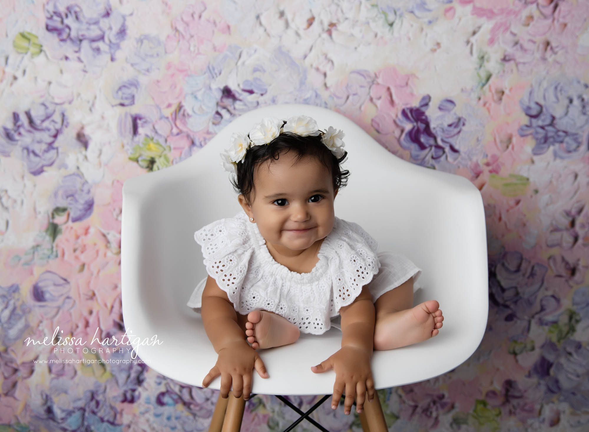 Baby girl sitting in chair leaning forward smiling Middletown CT Cake Smash Photographer
