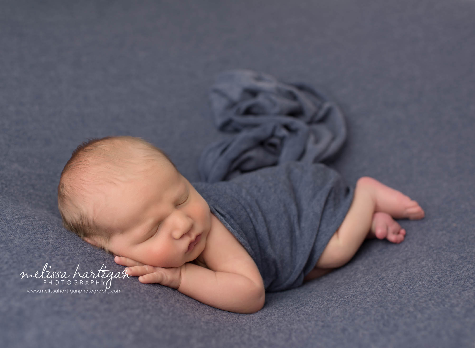 Newborn baby boy posed on side with blue layer wrap draped over New milford newborn Photographer