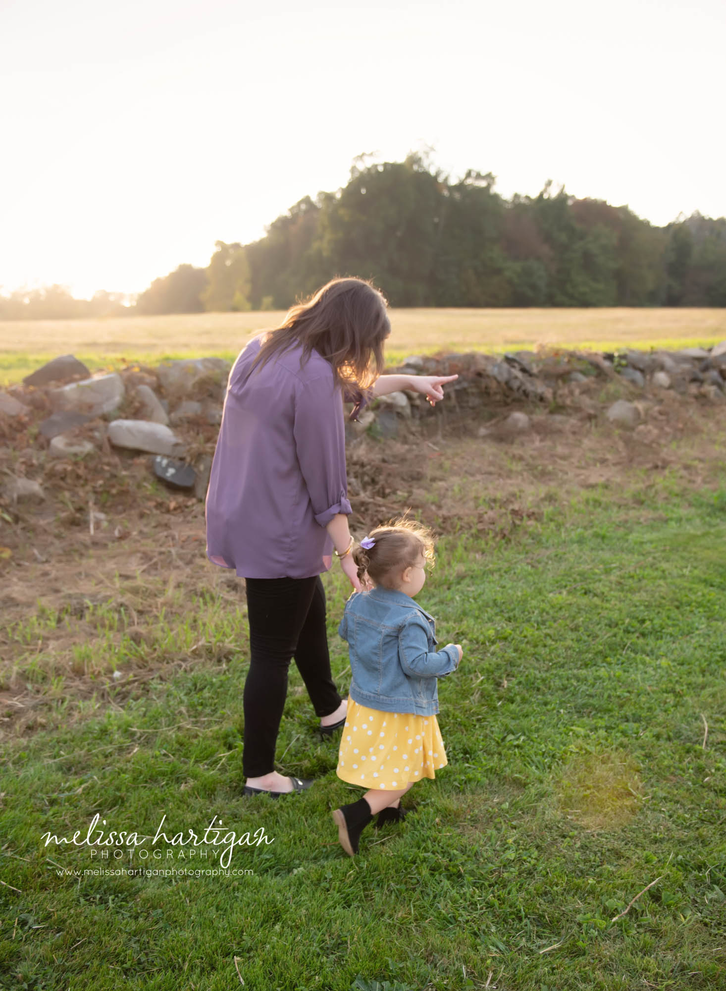 mom walking with toddler daughter in field family photo