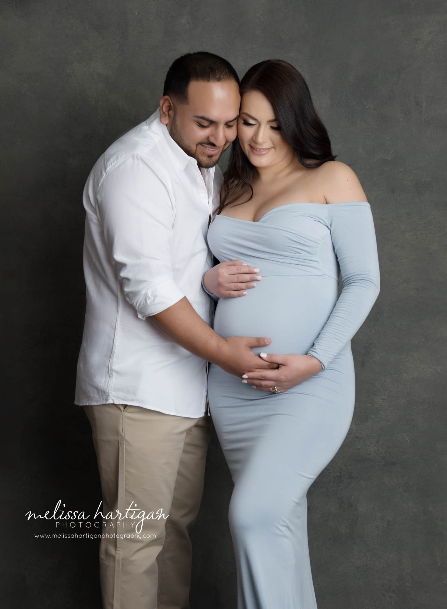 expectant couple holding baby bump in studio maternity couples pose photography session