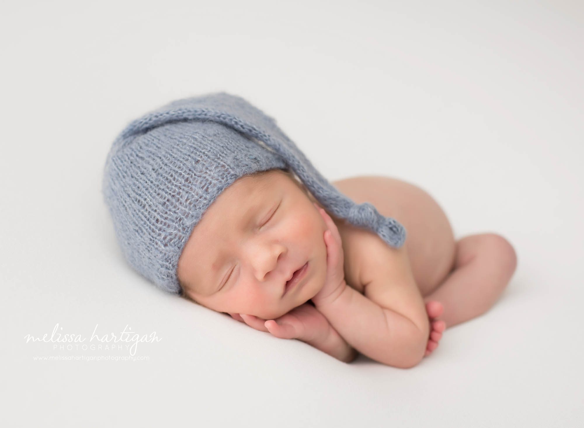 newborn baby boy posed with blue knitted sleepy cap