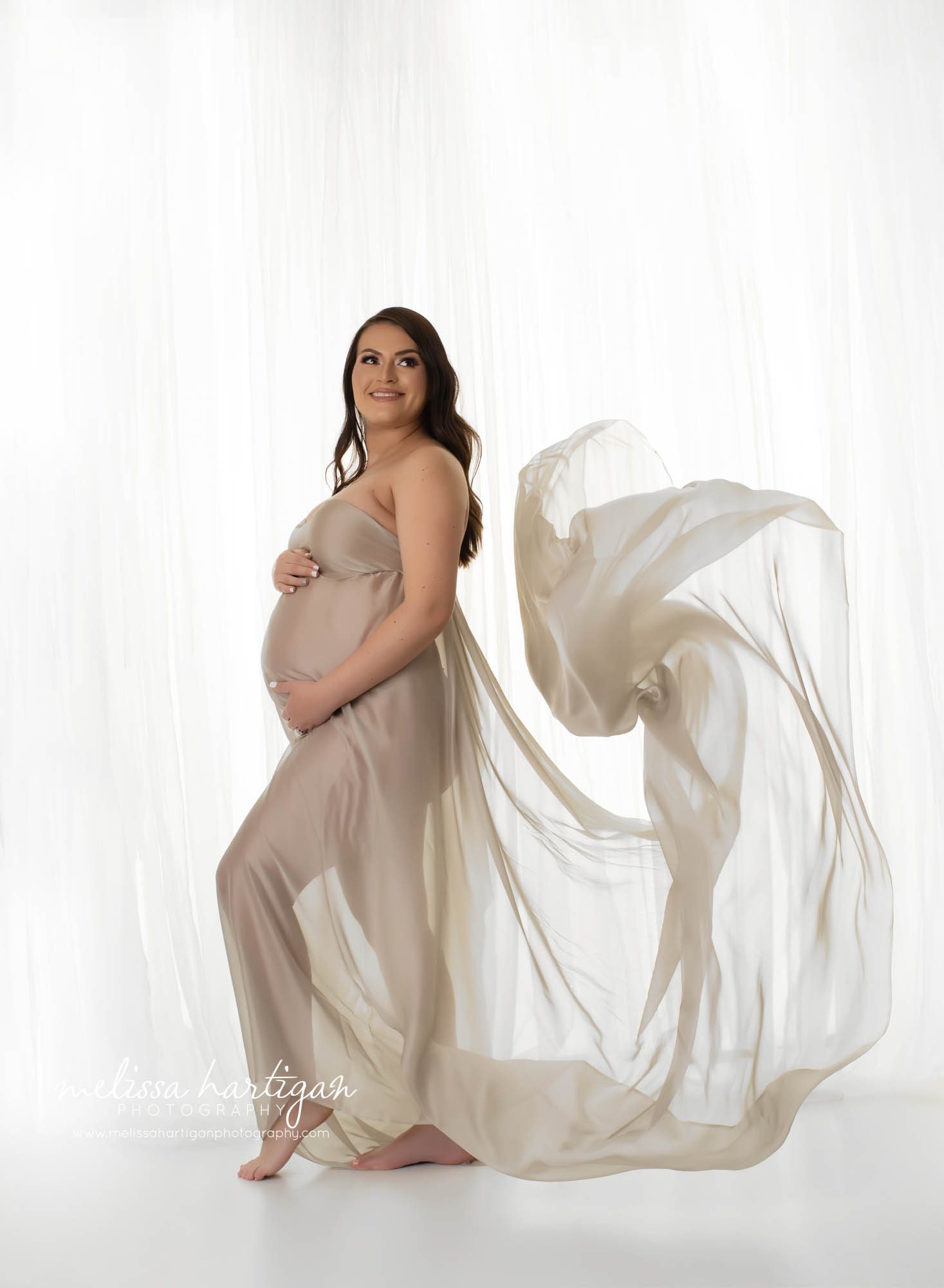 pregnant mom standing studio maternity pose draped in fabric