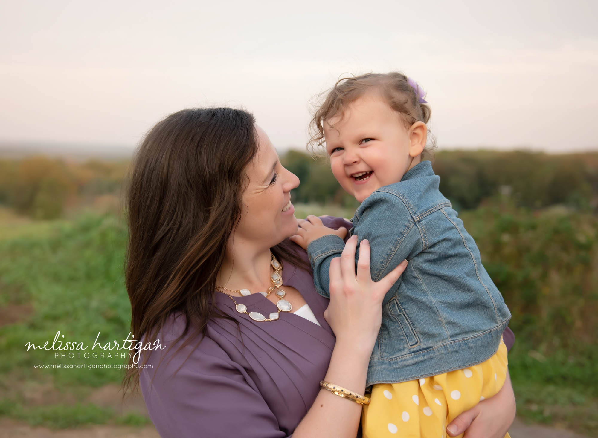 mom holding toddler daughter smiling and laughing together