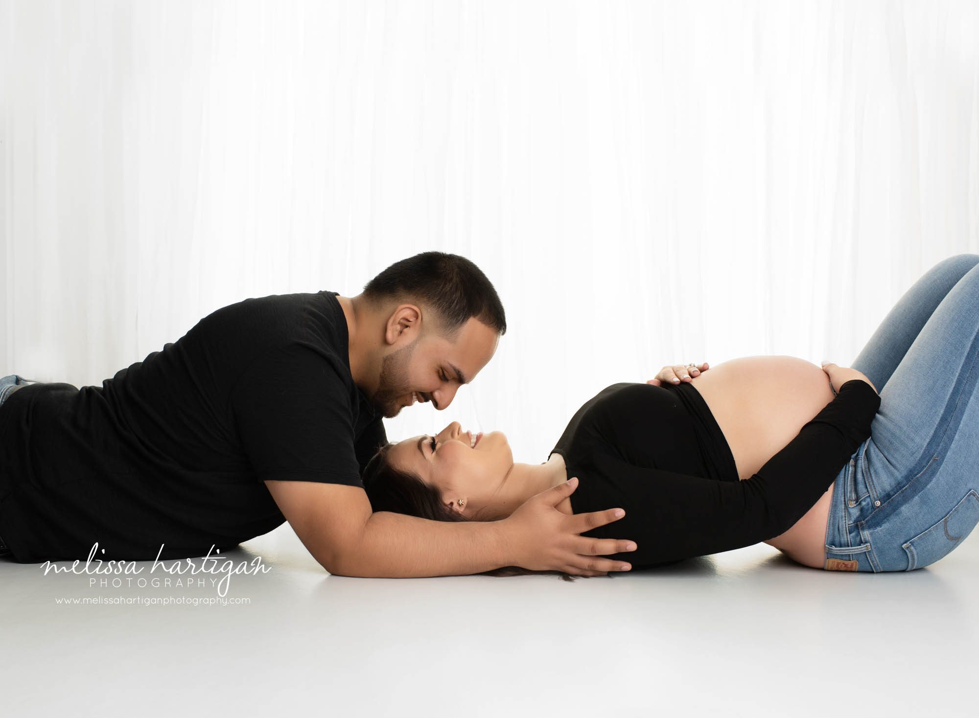 expectant couple laying on floor holding baby bump connection pose Manchester CT Maternity Photography
