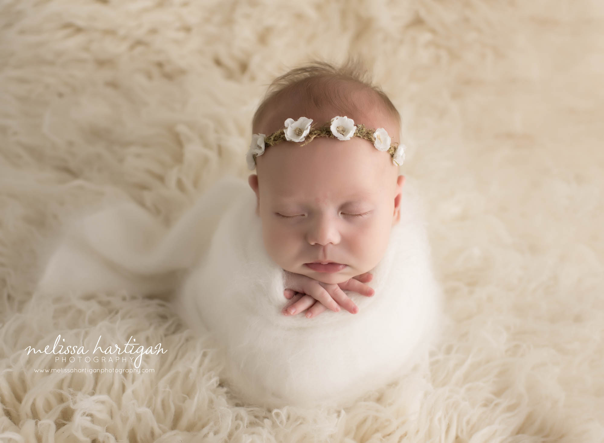 newborn baby girl wrapped in white wrap with flower headband