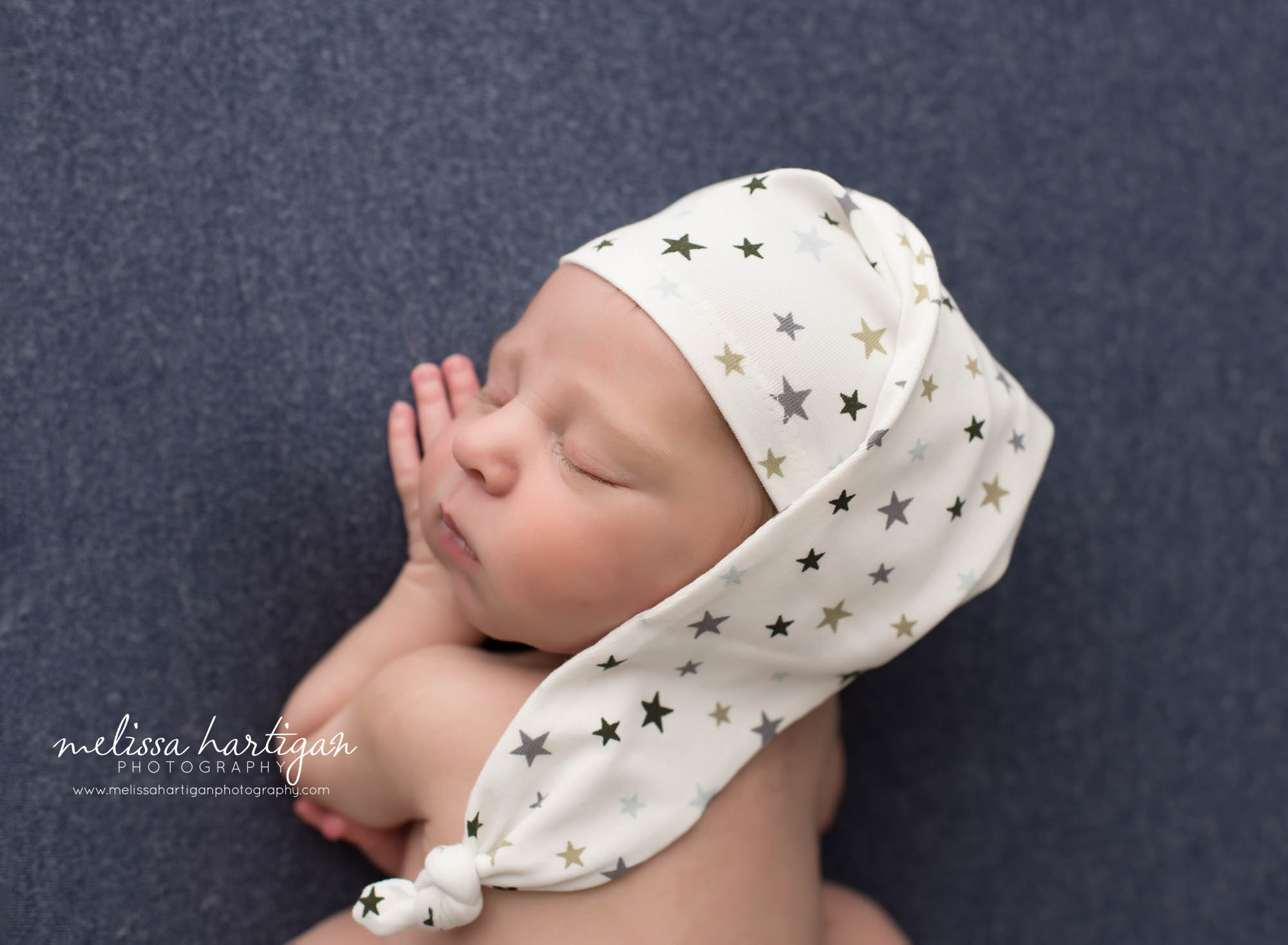 newborn baby boy posed on side with sleepy cap on