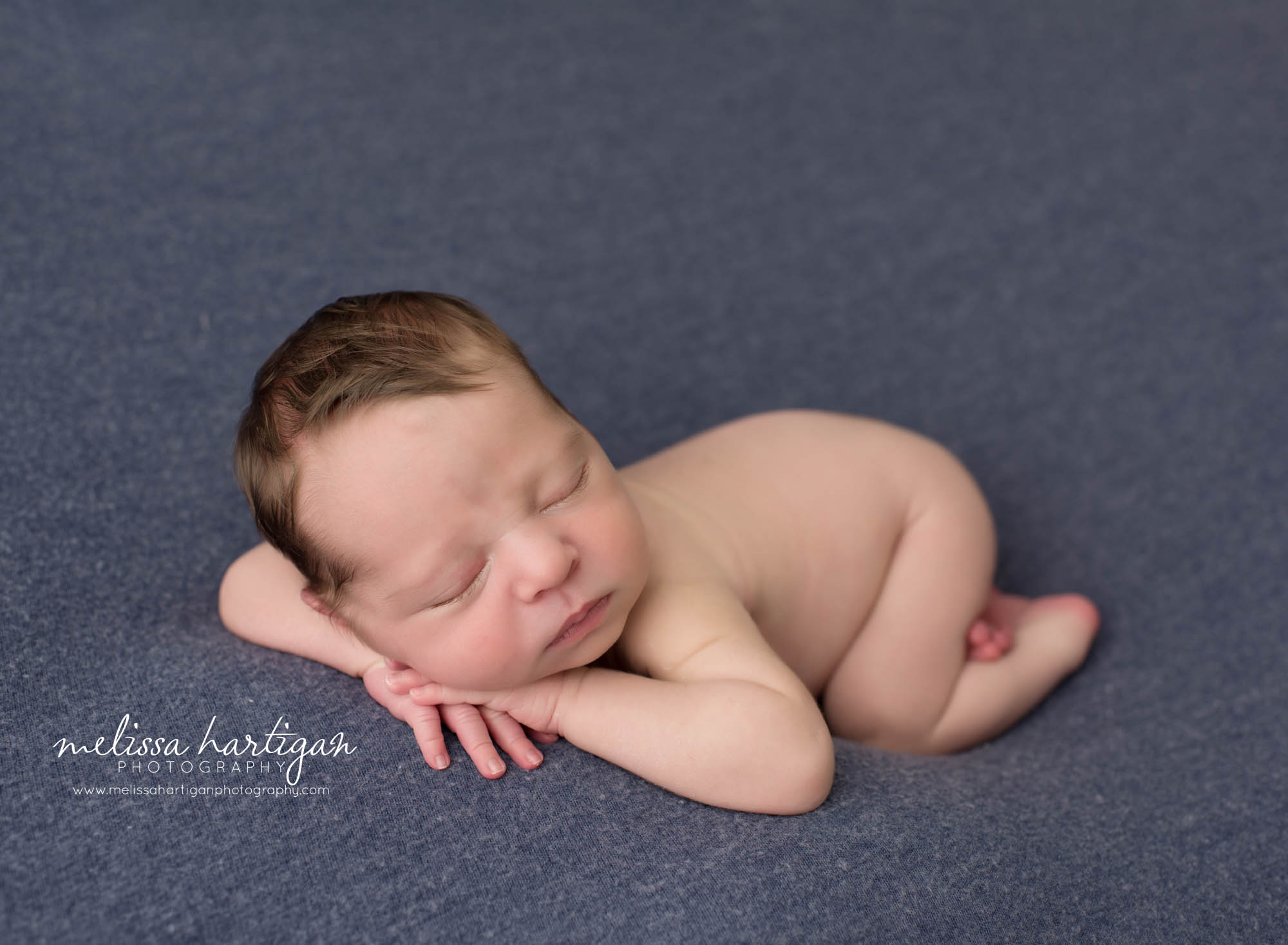 newborn baby boy posed with hea don hand side pose on back backdrop CT Newborn Photography